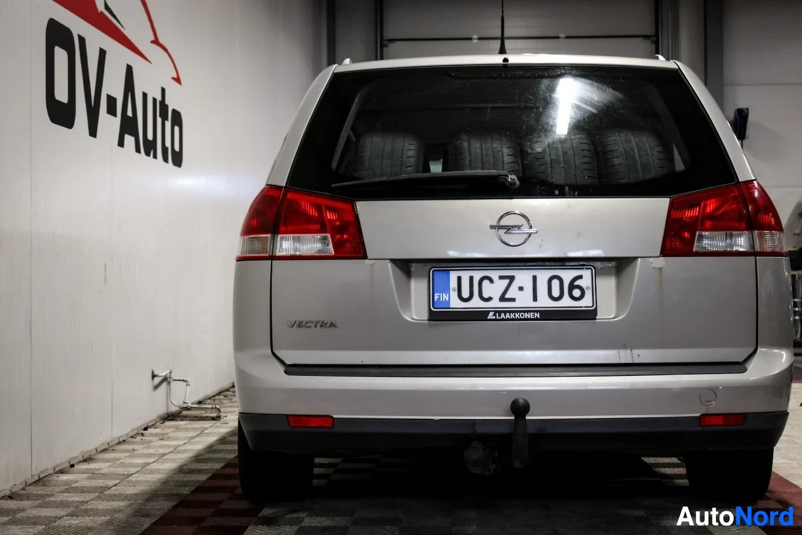 Takaa: Hopeanvärinen farmariauto takaa kuvattuna parkkihallissa. Rekisterikilpi on ja tavaratilassa näkyy neljä rengasta. Autossa on peräkoukku