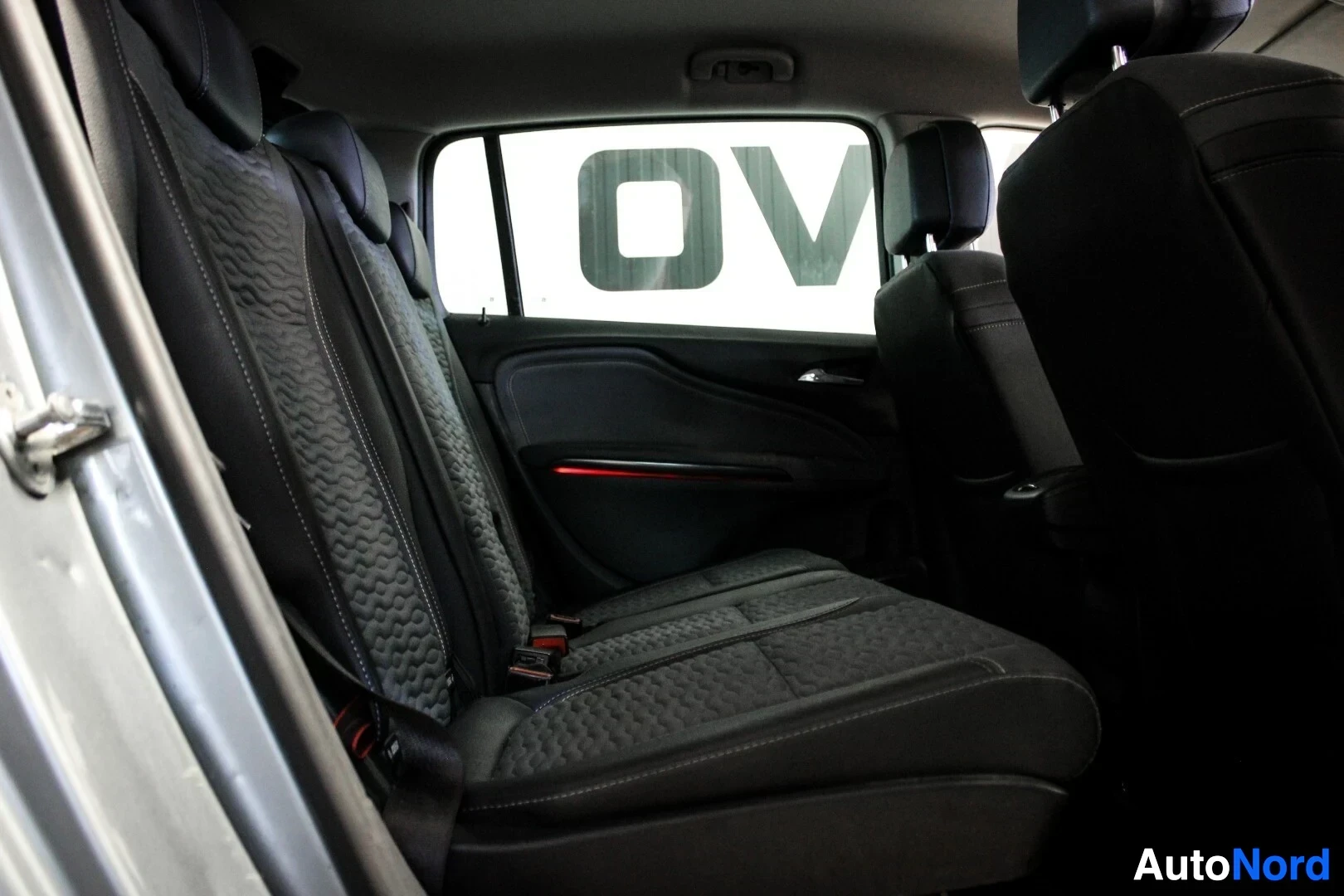 Ohjaamo: Auton sisätilat kuvattuna vasemmalta takaapäin. Näkyvissä on takaistuimet ja punaisena hehkuva valolista oven sisäpuolella.