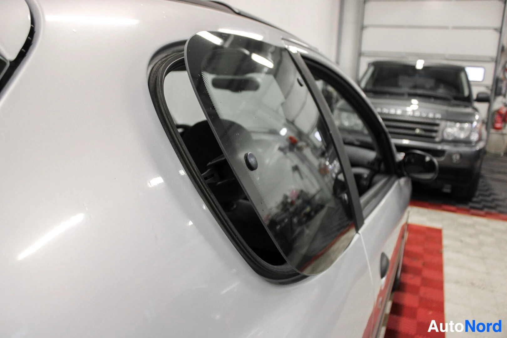 Yksityiskohta: Detailikuva Peugeot 206:n takaosan sivuikkunasta, joka on raollaan.