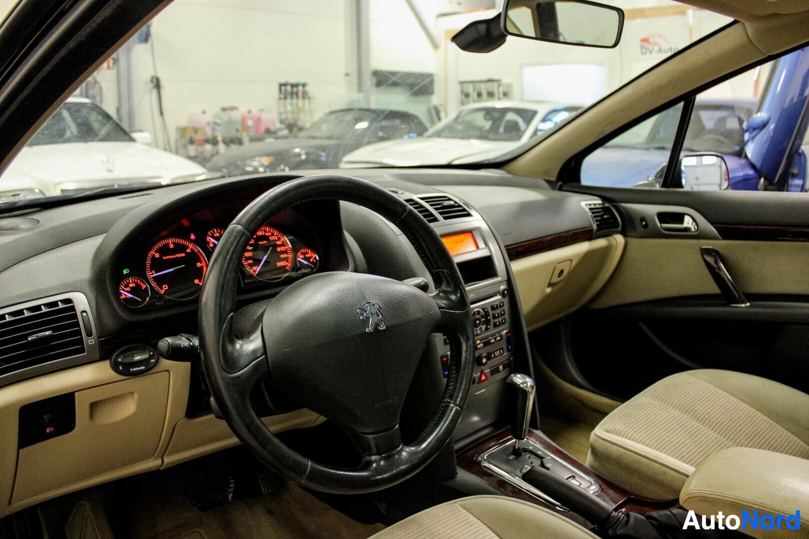 Ohjaamo: Kuvakulma mustan Peugeot 407 -auton etumatkustajan puolelta, näyttäen ohjaamon etuosan. Ohjauspyörässä on monitoimipainikkeet ja mittaristo näkyy selvästi.