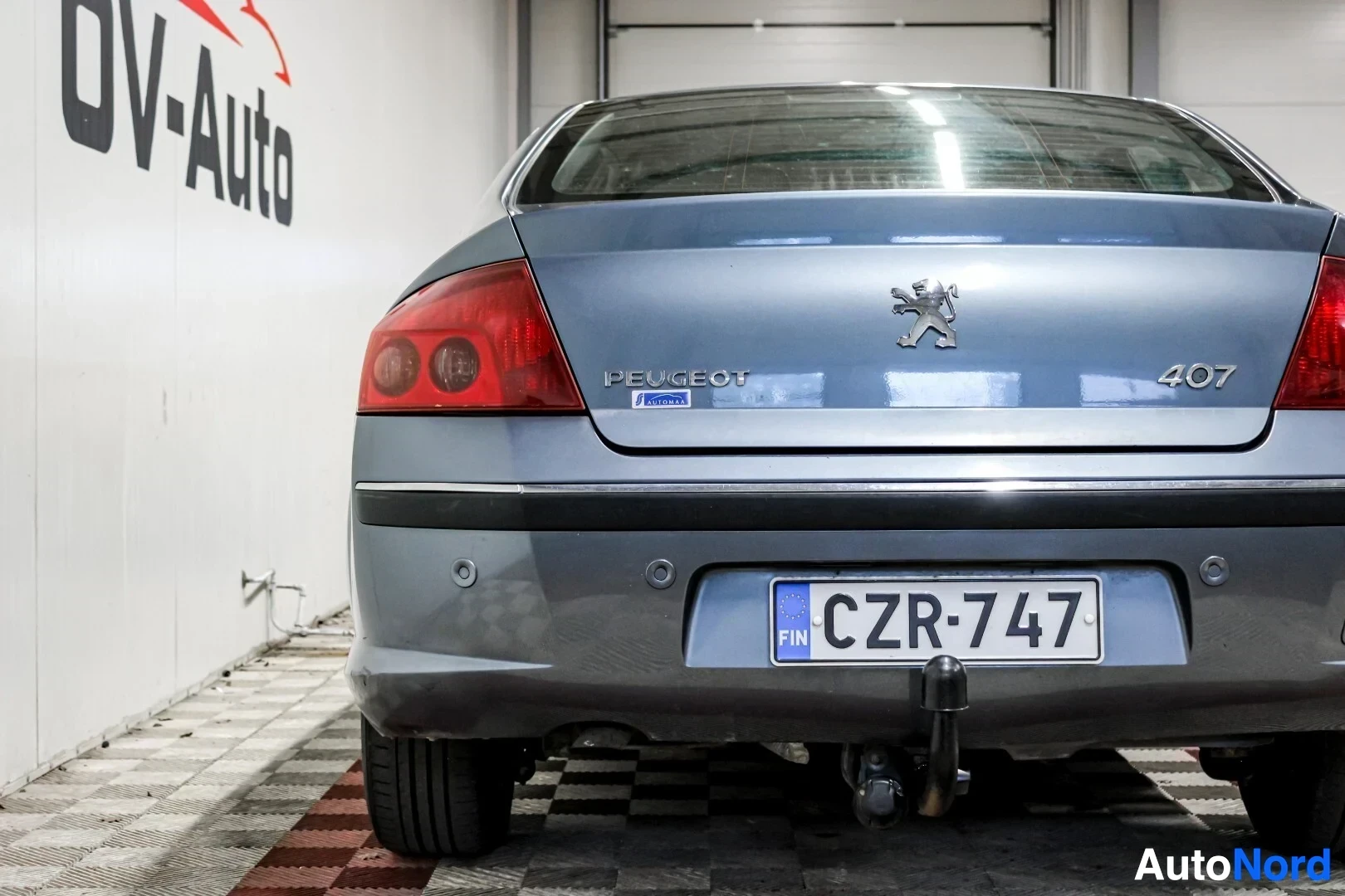 Takaa: Peugeot 407 sedanin takaosa, jossa rekisterikilpi, vetokoukku ja peruutustutkat