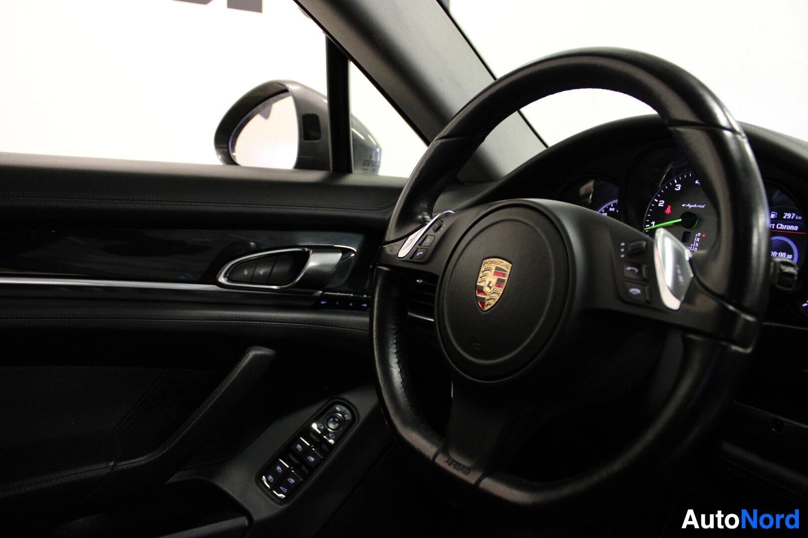Ohjaamo: Kuva auton ohjauspyörästä ja kuljettajan ovesta. Ohjauspyörän keskellä on Porsche-logo ja sen takana näkyy auton mittaristo. Kuljettajan oven sisäpaneelissa on