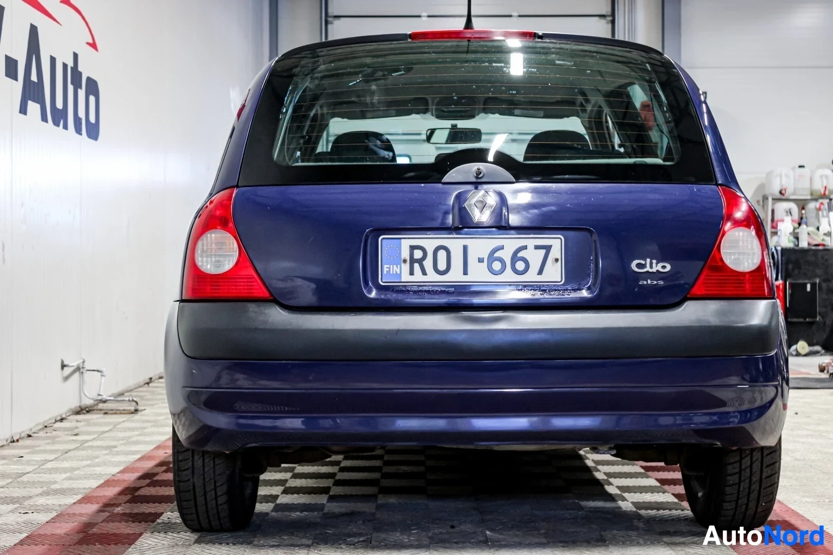 Takaa: Sinisen viisiovisen hatchback-auton takaosa on kuvattu suoraan takaa. Rekisterikilvessä lukee "". Takaluukun vasemmalla puolella on "Clio" ja "ABS" -merk