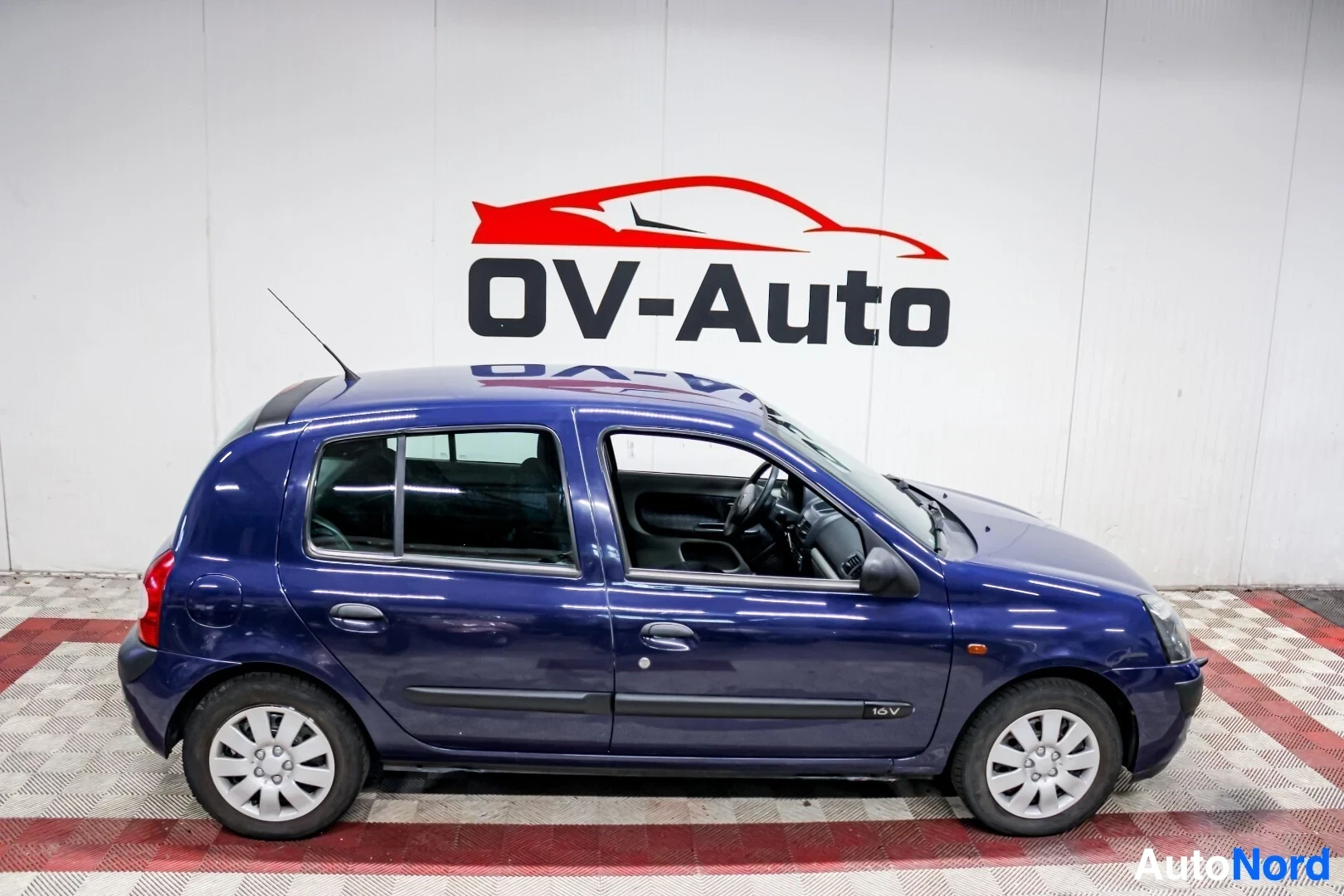 Sivulta: Sininen viisiovinen hatchback-auto on kuvattu oikealta kyljeltä. Auton ovet, ikkunat ja renkaat ovat näkyvissä. Oikean etulokasuojan alaosassa on "16V"-merkintä