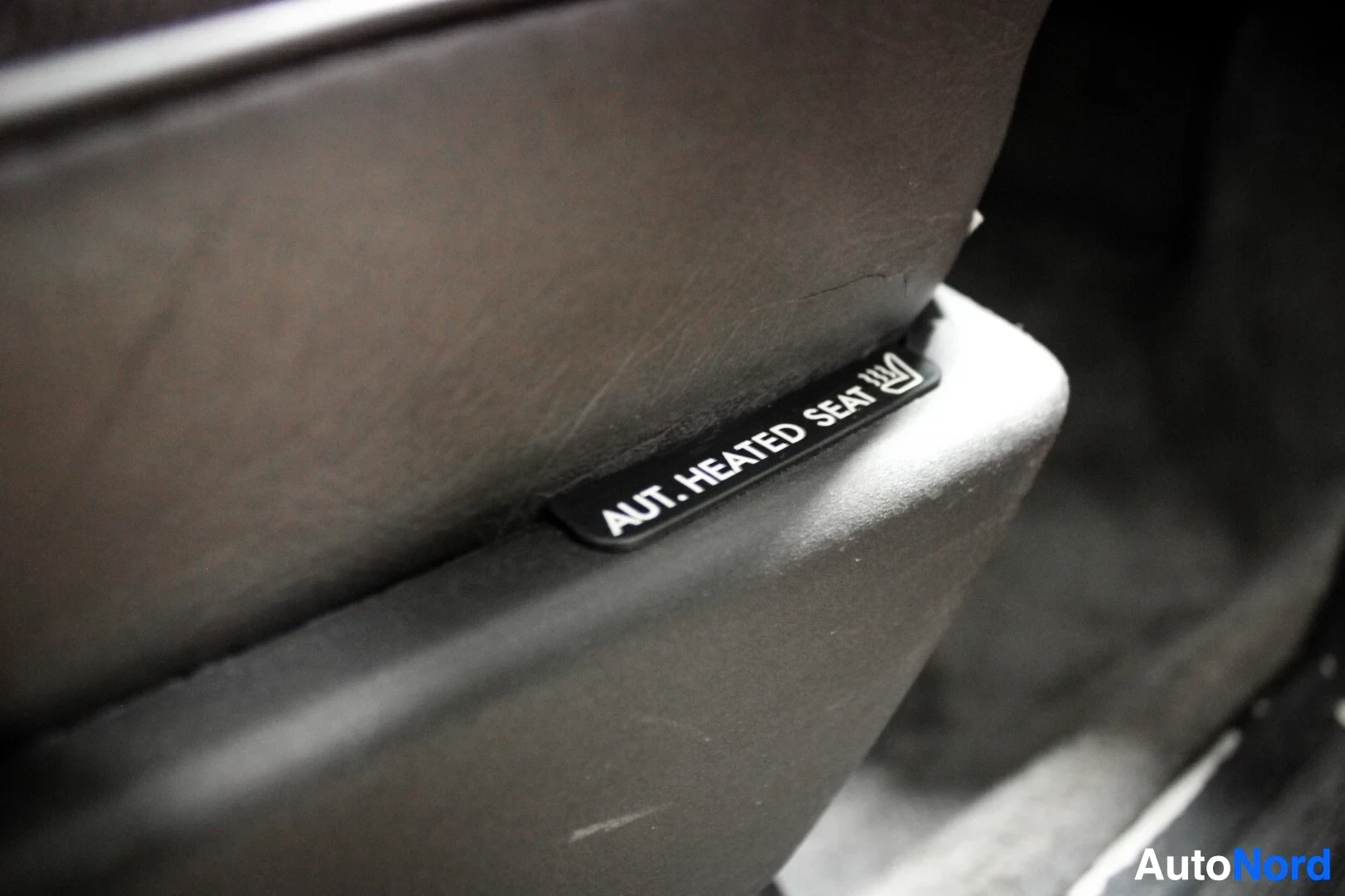 Yksityiskohta: Lähikuva istuimen sivupaneelista, jossa on tarra "AUT. HEATED SEAT".
