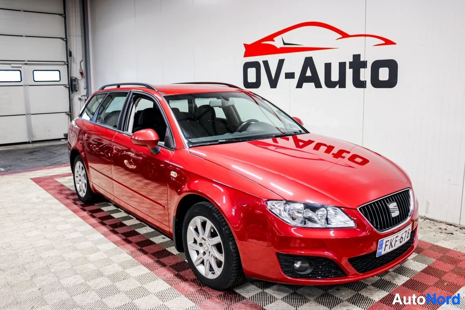 Etuviisto, nokka oikealle: Punainen Seat Exeo ST -farmari kuvattu kolmivartaloasennossa edestä oikealta autotallin sisällä.
