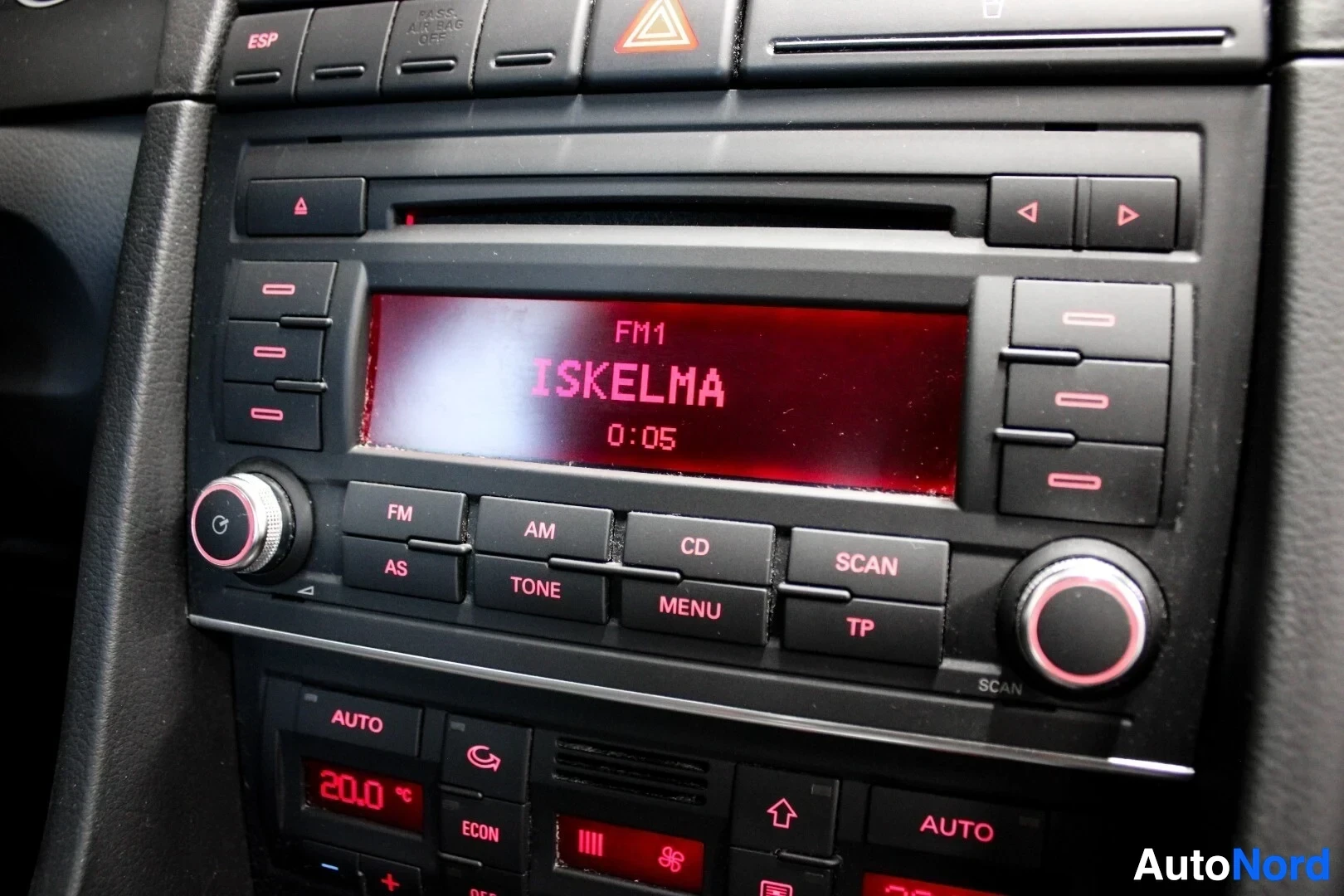 Yksityiskohta: Lähikuva keskikonsolin radiosta ja ilmastoinnin säätimistä. Radionäytöllä lukee "FM1 ISKELMA 0:05".