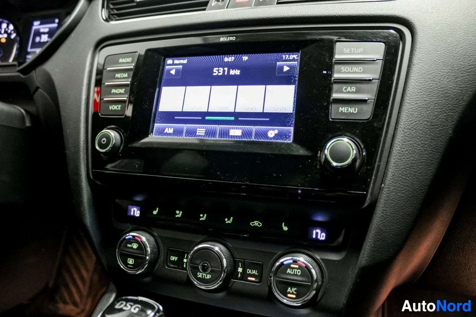 Yksityiskohta: Lähikuva auton keskikonsolista, jossa näkyy kosketusnäytöllinen radio/infotainment-järjestelmä ja automaatti-ilmastoinnin säätimet.