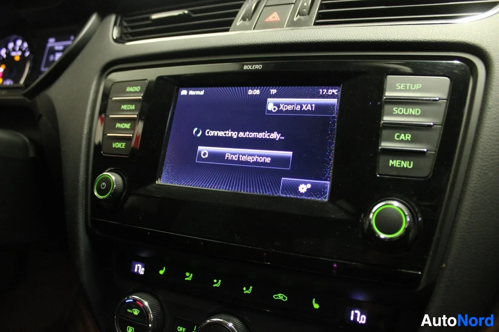 Yksityiskohta: Lähikuva auton keskikonsolin infotainment-näytöstä, joka näyttää puhelimen yhdistämisen tilan ja 'BOLERO' -tekstin.