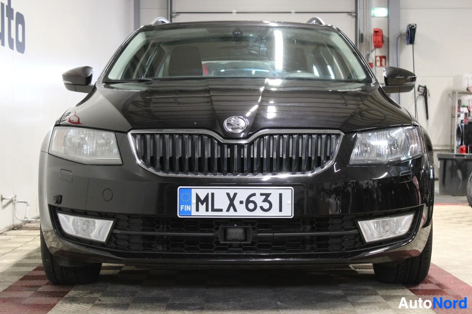 Edestä: Musta Skoda Octavia Combi edestä päin kuvattuna. Ajovalot, etusäleikkö ja etupuskuri ovat näkyvissä. Rekisterikilpi '' on keskellä