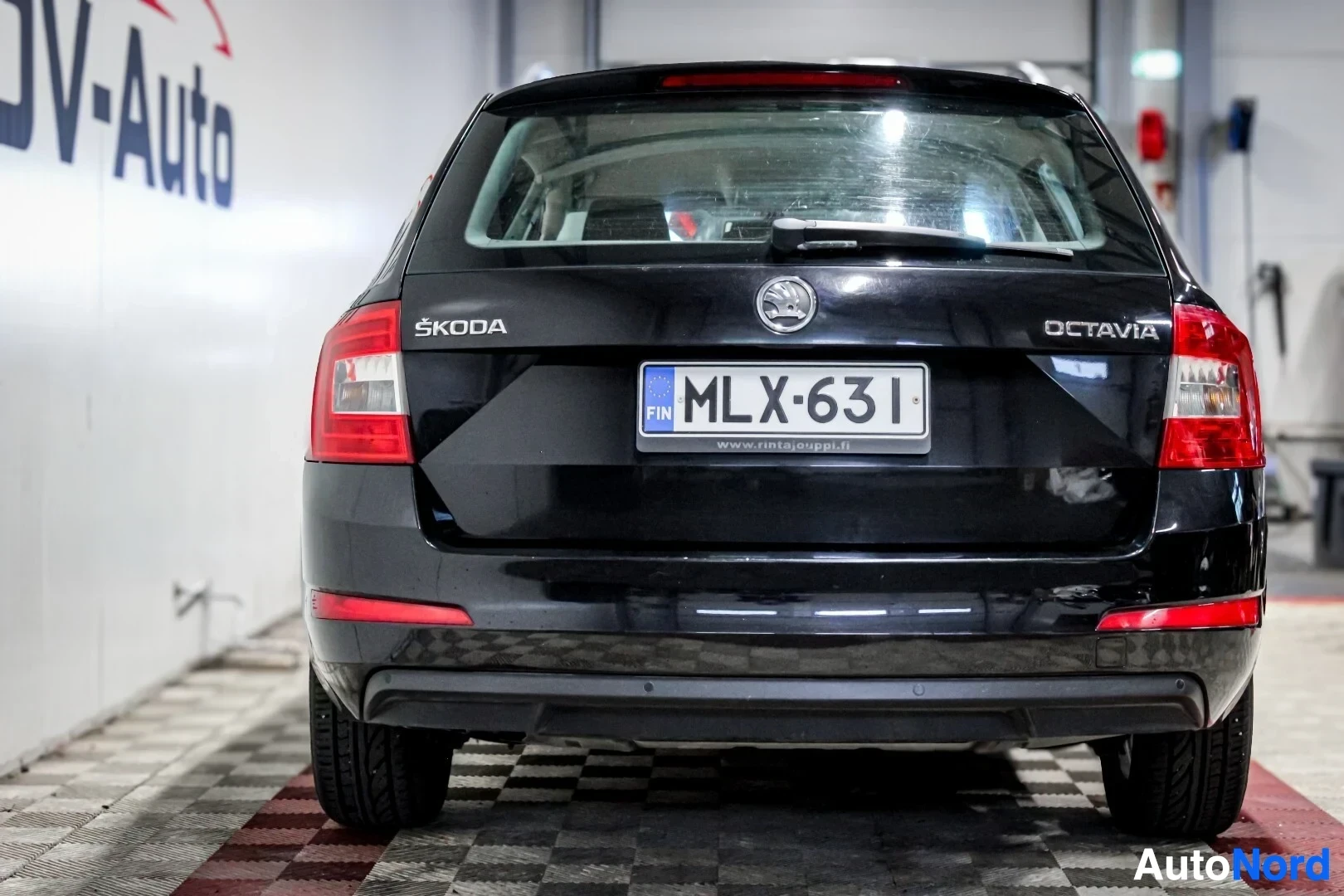 Takaa: Musta Skoda Octavia farmari auton takaosa kuvattuna suoraan takaa. Rekisterikilpi näkyy takaluukussa