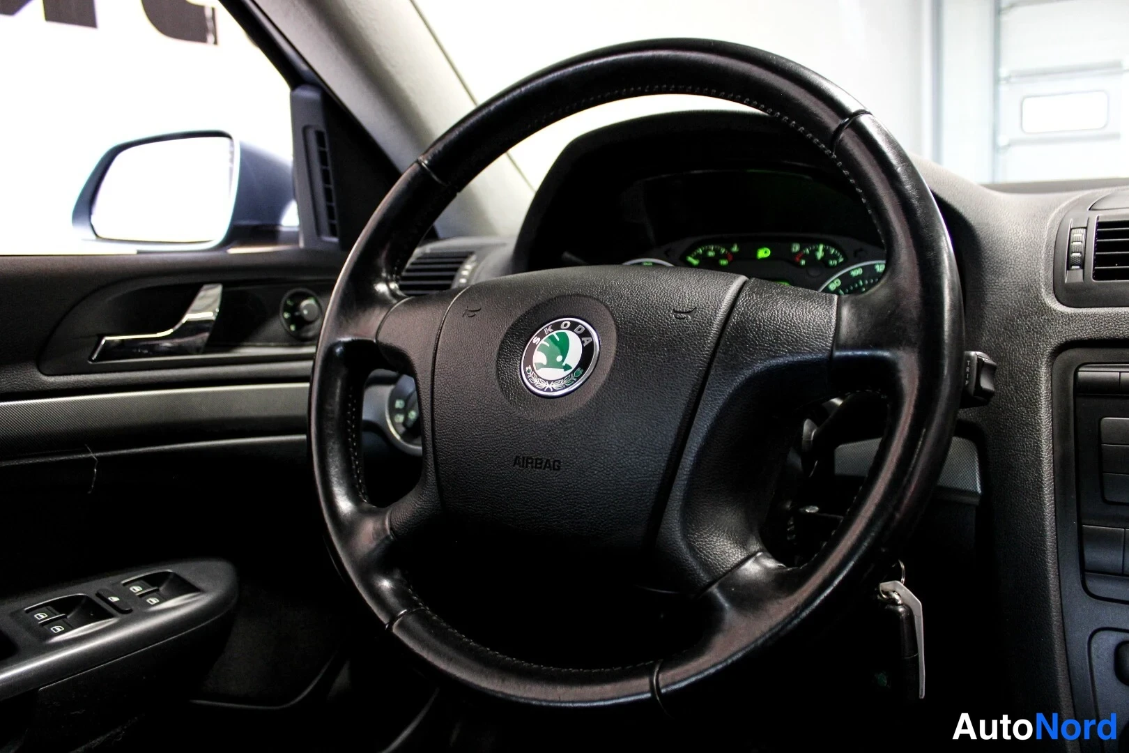 Muu: Lähikuva Škoda-merkillisestä ohjauspyörästä, jossa AIRBAG-teksti; takana kojelaudan mittarit.