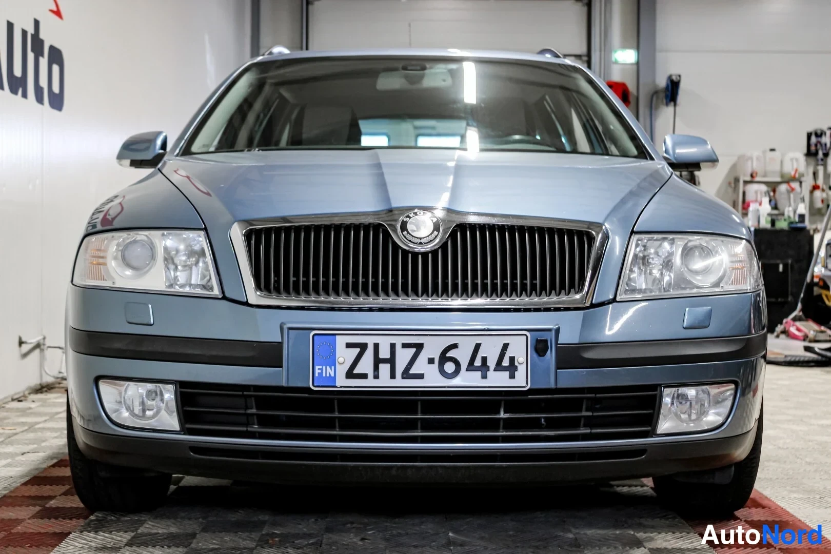 Edestä: Sininen auto suoraan edestä kuvattuna, rekisterikilpi FIN.
