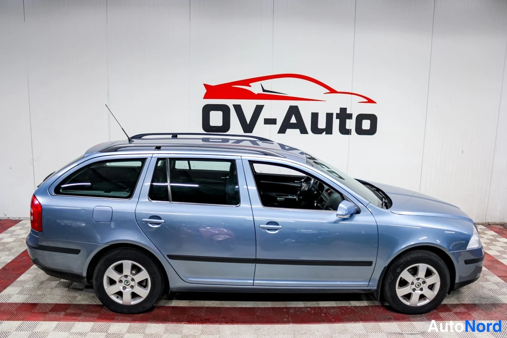 Sivulta: Sininen Skoda Octavia Combi sivulta kuvattuna sisätiloissa, katukehäkatolla ja viisiovainen korirakenne näkyvissä.