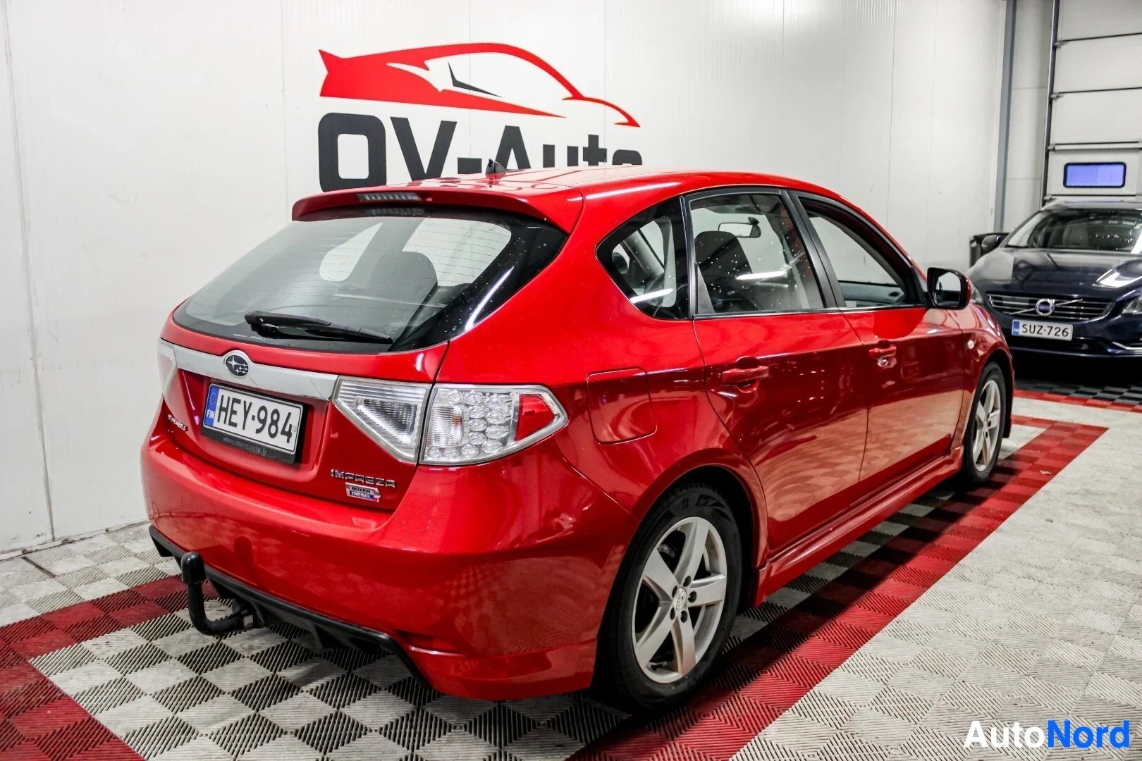 Takaviisto: Punainen Subaru Impreza viistoperäinen auto takaa kolmevarttikevystä. Autossa on vetokoukku, kevytmetallivanteet ja takaspoileri. Rekisterikilpi "" on nä