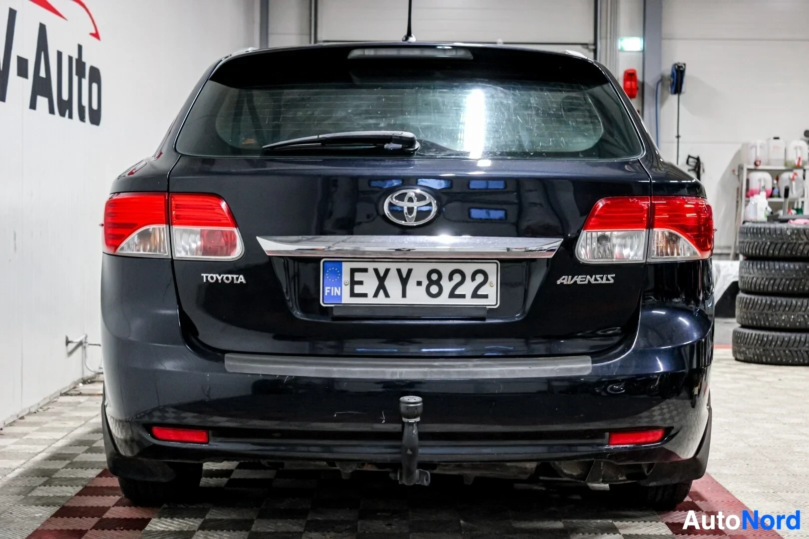 Takaa: Tummanvärinen farmariauto takaa päin kuvattuna parkkihallissa. Autossa on peräkoukku ja rekisterikilpi ""