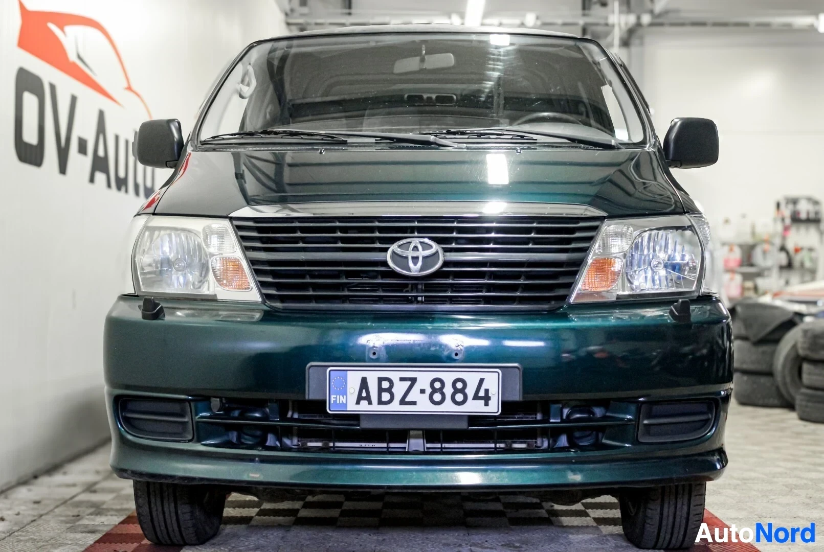 Edestä: Tummanvihreä pakettiauto edestä päin kuvattuna. Keulassa on Toyota-logo ja rekisterikilpi ""