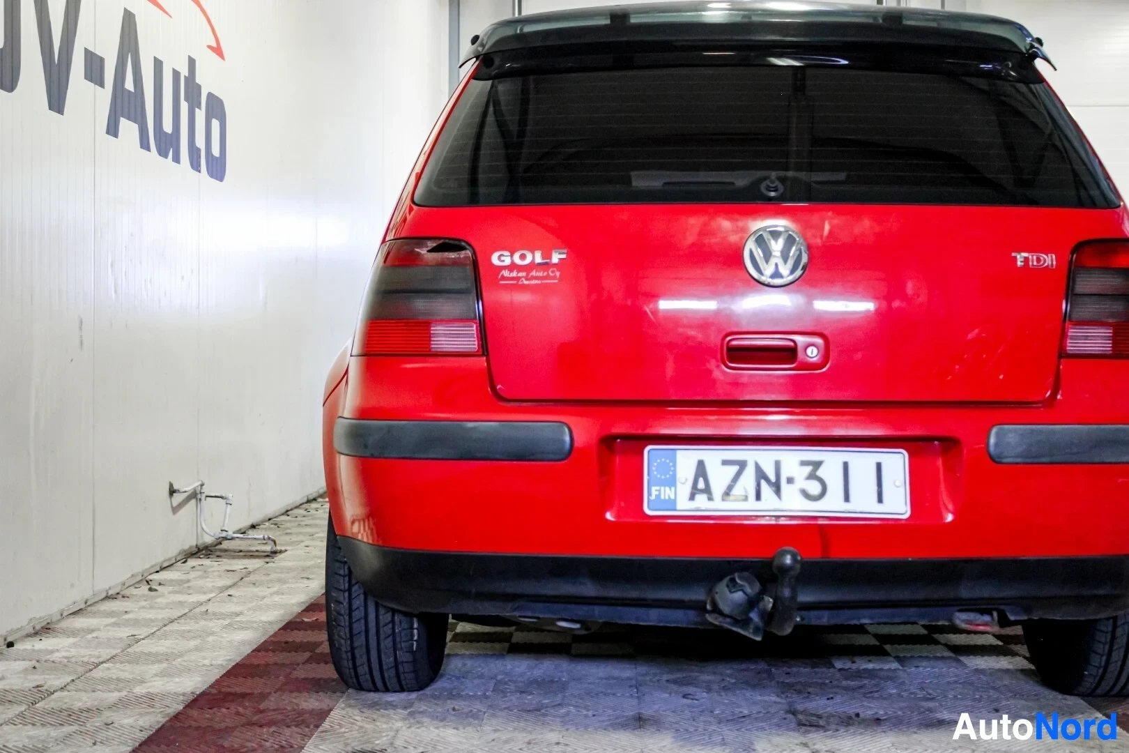 Takaa: Punaisen henkilöauton takaosa on kuvattu suoraan takaa. Rekisterikilvessä lukee. Takaluukussa on Volkswagen-logo, 'GOLF' ja 'TDI' -merkinnät. Autossa on