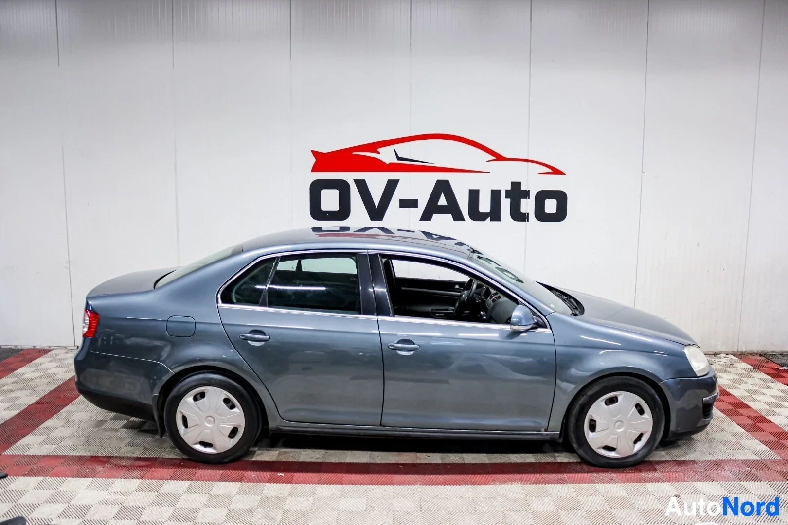 Sivulta: Harmaa henkilöauto kuvattuna oikealta sivulta. Autossa on valkoiset pölykapselit.