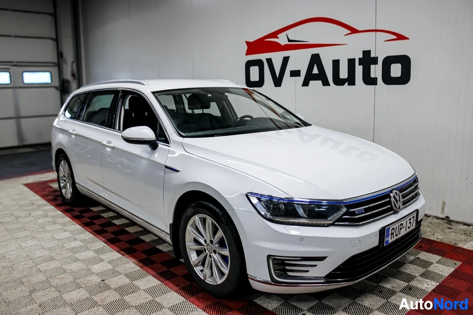 Etuviisto, nokka oikealle: Valkoinen Volkswagen Passat Variant GTE etuvasemmalta kuvattuna OV-Auton myymälässä.