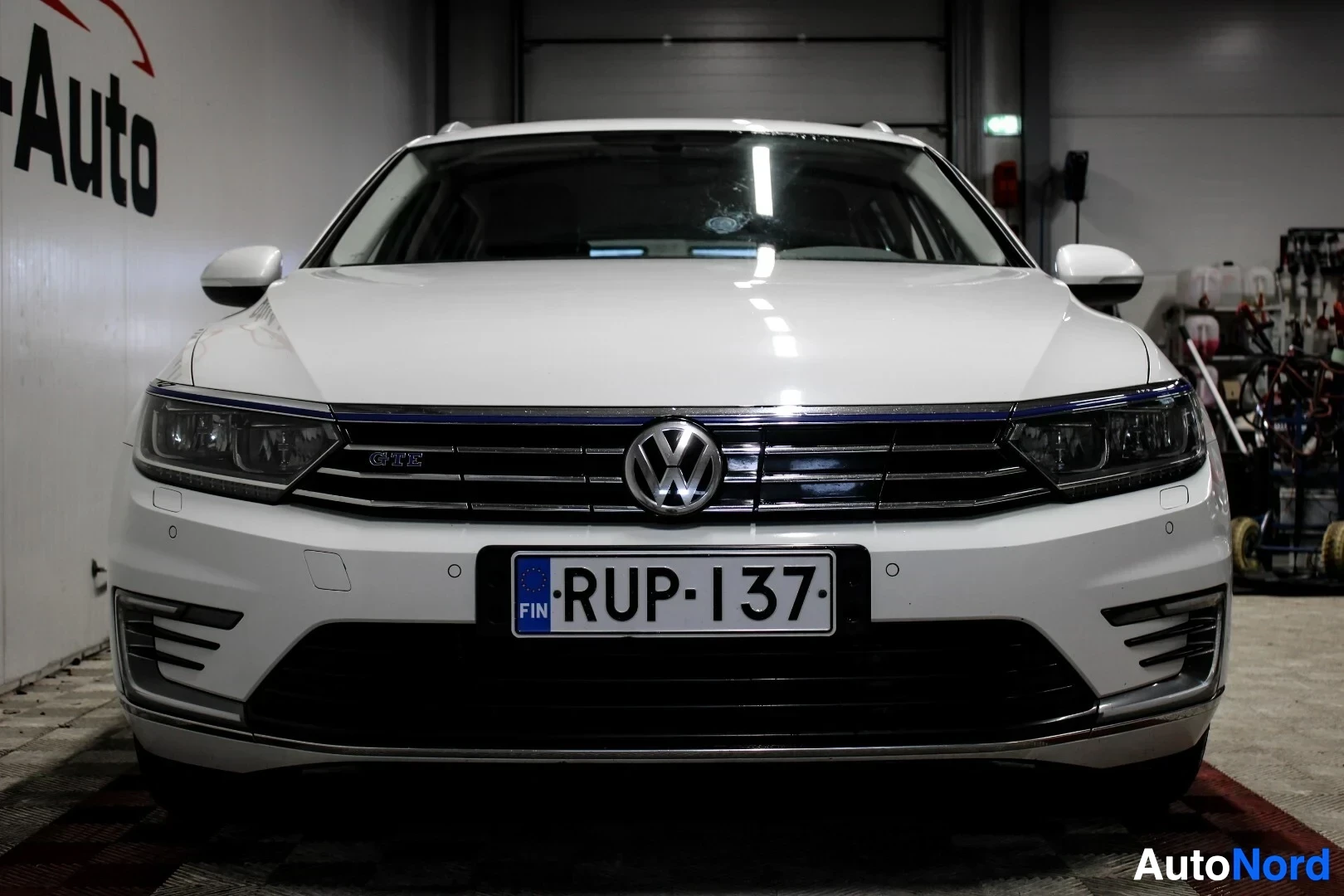 Edestä: Valkoisen Volkswagen Passat Variantin etuosa keskeltä kuvattuna. Rekisterikilpi näkyy