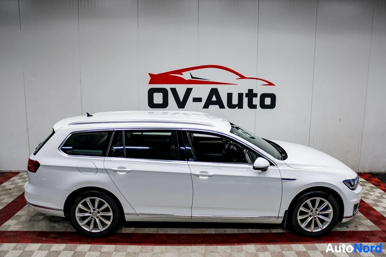 Sivulta: Valkoinen farmariauto vasemmalta sivulta kuvattuna. Autossa on kattokaiteet ja kevytmetallivanteet.