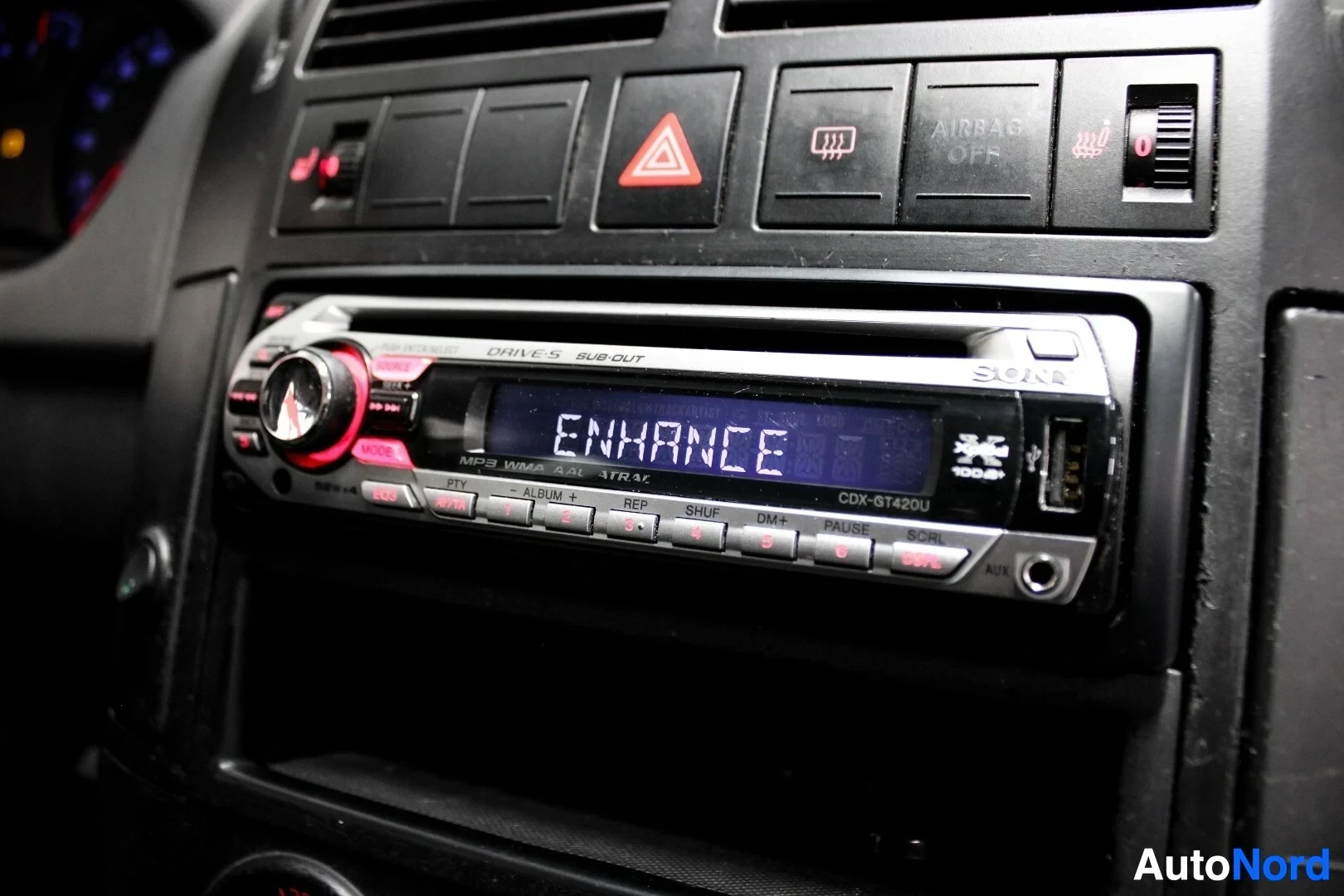 Yksityiskohta: Auton radio, jonka näytöllä lukee "ENHANCE" ja "CDX-GT420U". Radio on merkkiä Sony.