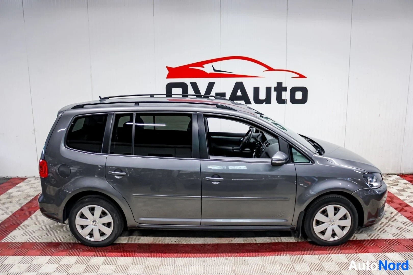 Sivulta: Harmaa henkilöauto kuvattuna oikealta sivulta. Siinä on kattokaiteet ja kevytmetallivanteet.
