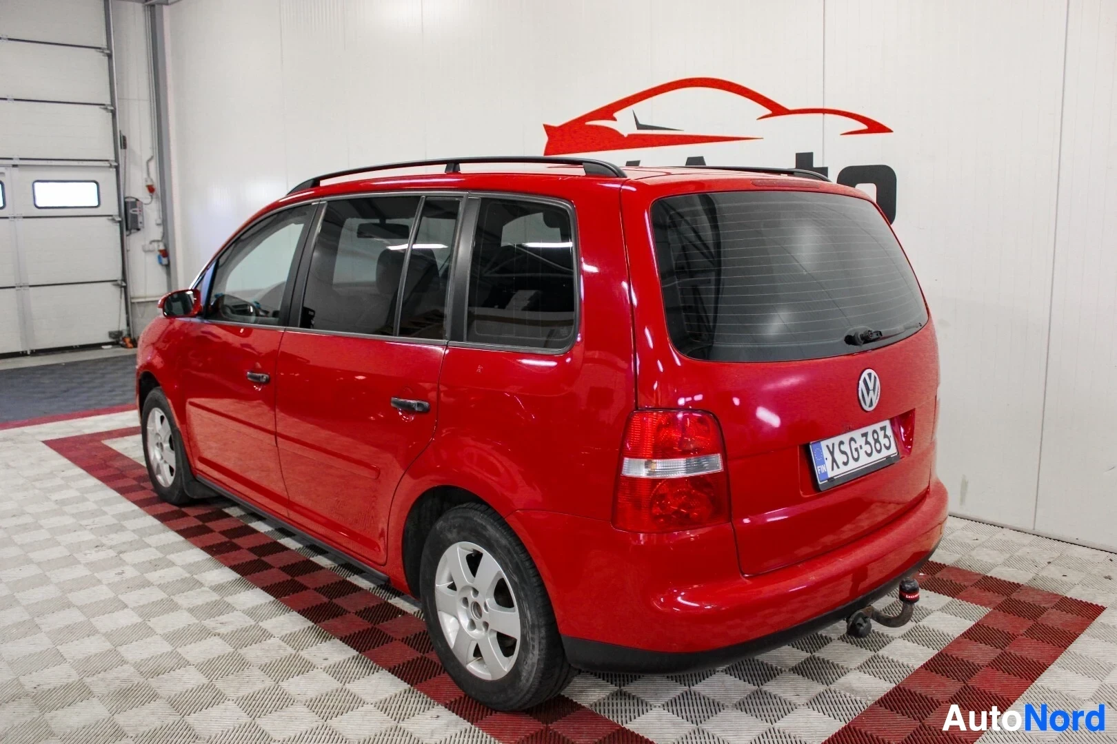 Takaviisto: Punaisen Volkswagen-henkilöauton takaosa ja oikea kylki. Autossa on kattokiskot, vetokoukku ja kevytmetallivanteet.