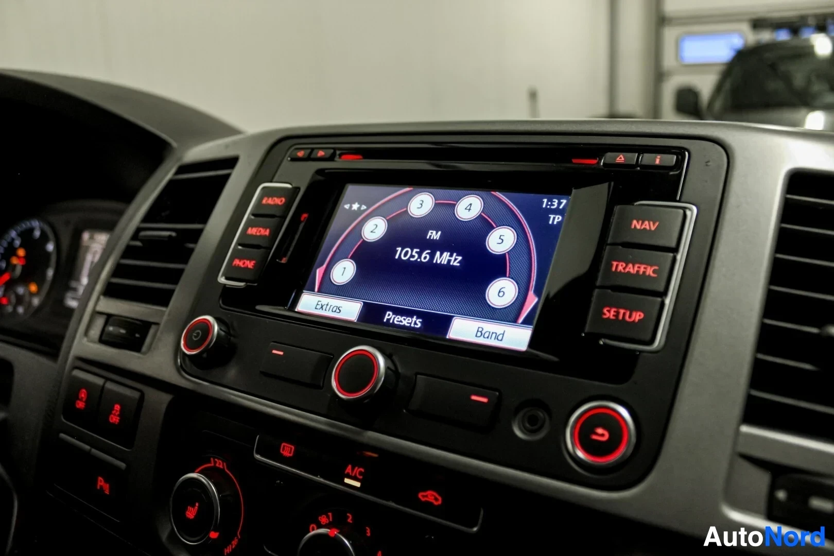 Ohjaamo: Lähikuva auton keskinäytöstä, jossa näkyy radiokanavan valinta FM 105.6 MHz. Näytön ympärillä on painikkeita RADIO, MEDIA, PHONE, NAV, TRAFFIC ja SETUP.