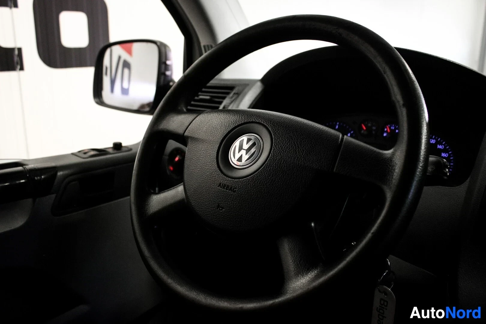 Ohjaamo: Musta kolmipuolainen ohjauspyörä Volkswagen-logolla, jossa lukee "AIRBAG" keskellä. Ohjauspyörän taakse jää mittariston yläosa. Kuvassa näkyy myös osia kojelaud