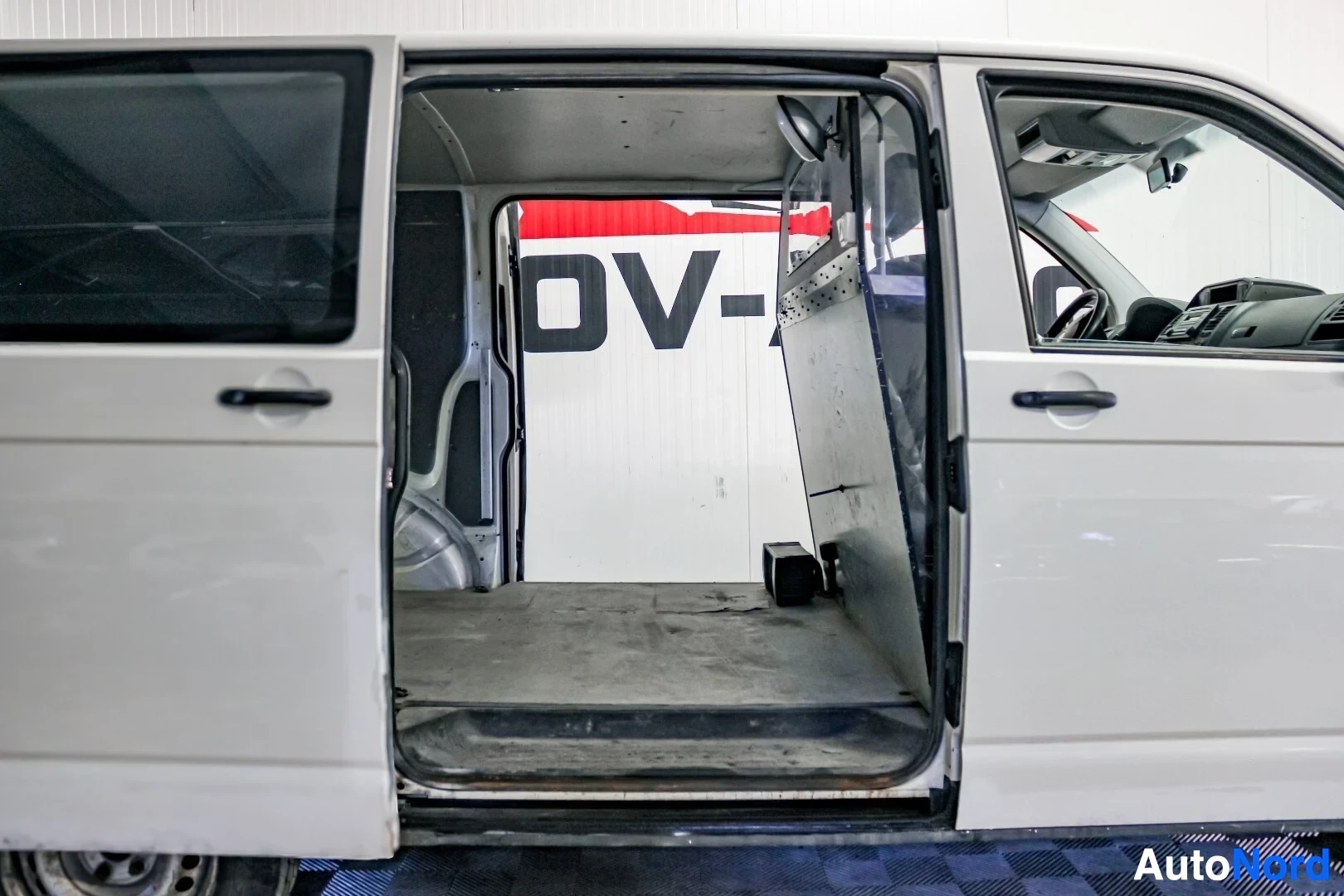 Sivulta: Sivukuva pakettiautosta, jonka liukuovi on auki, paljastaen tyhjän tavaratilan ja sisäpuolelle asennetun väliseinän.