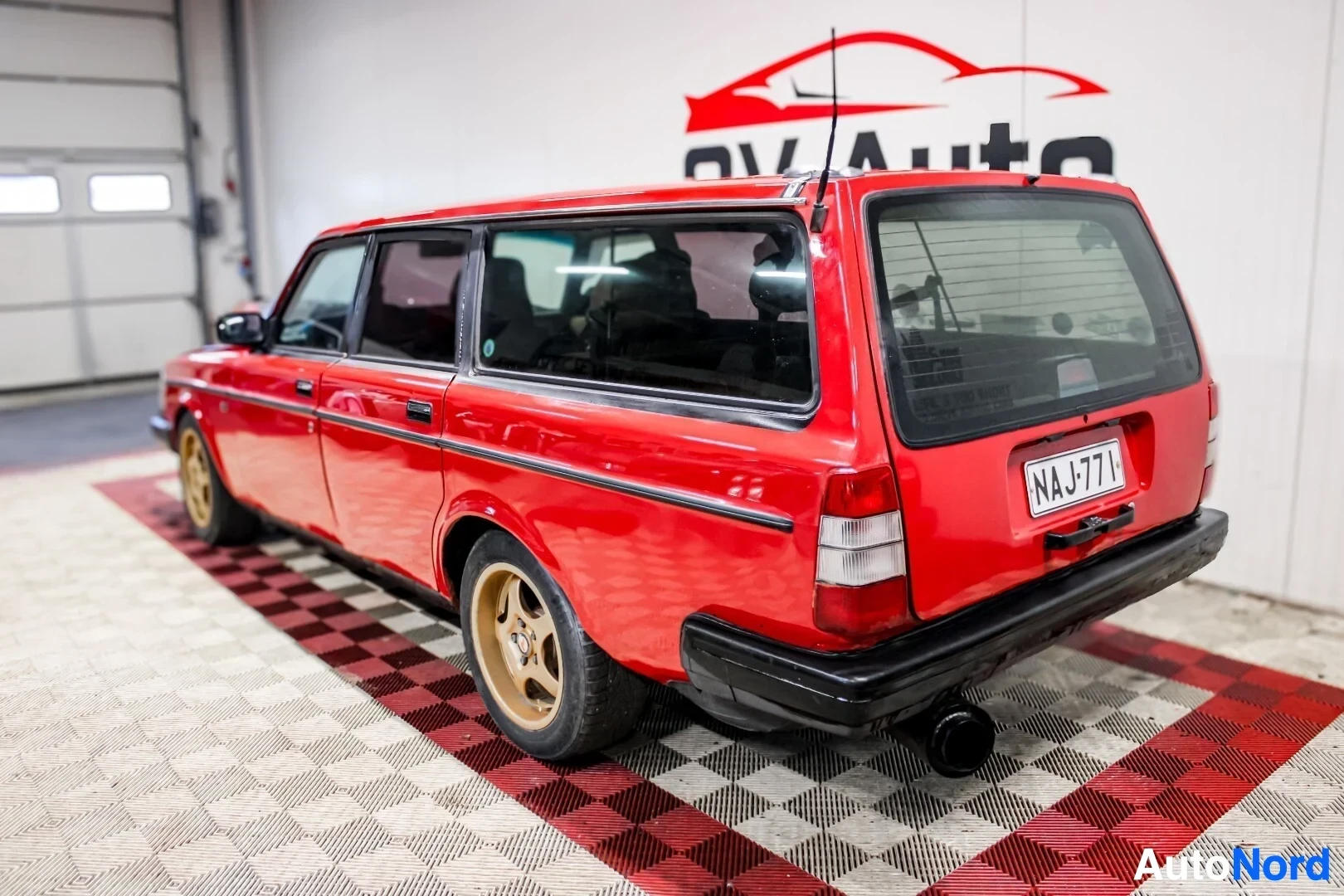 Takaviisto: Punainen farmariauto takaa ja oikealta viistosti kuvattuna. Autossa on kultaiset vanteet ja rekisterikilpi