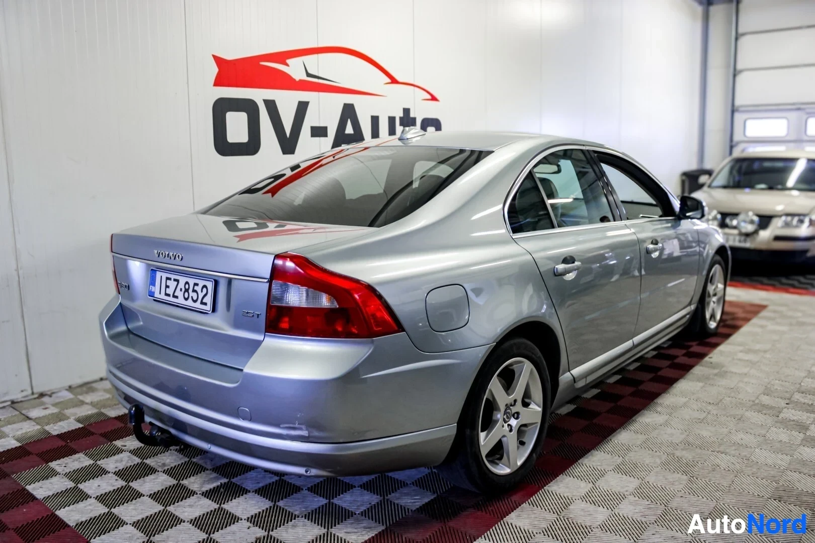Takaviisto: Hopeanvärinen sedan-auto kuvattuna takaa oikealta. Rekisterikilpi "" ja vetokoukku näkyvät. Takavalot ja peräkontin kansi ovat kuvassa