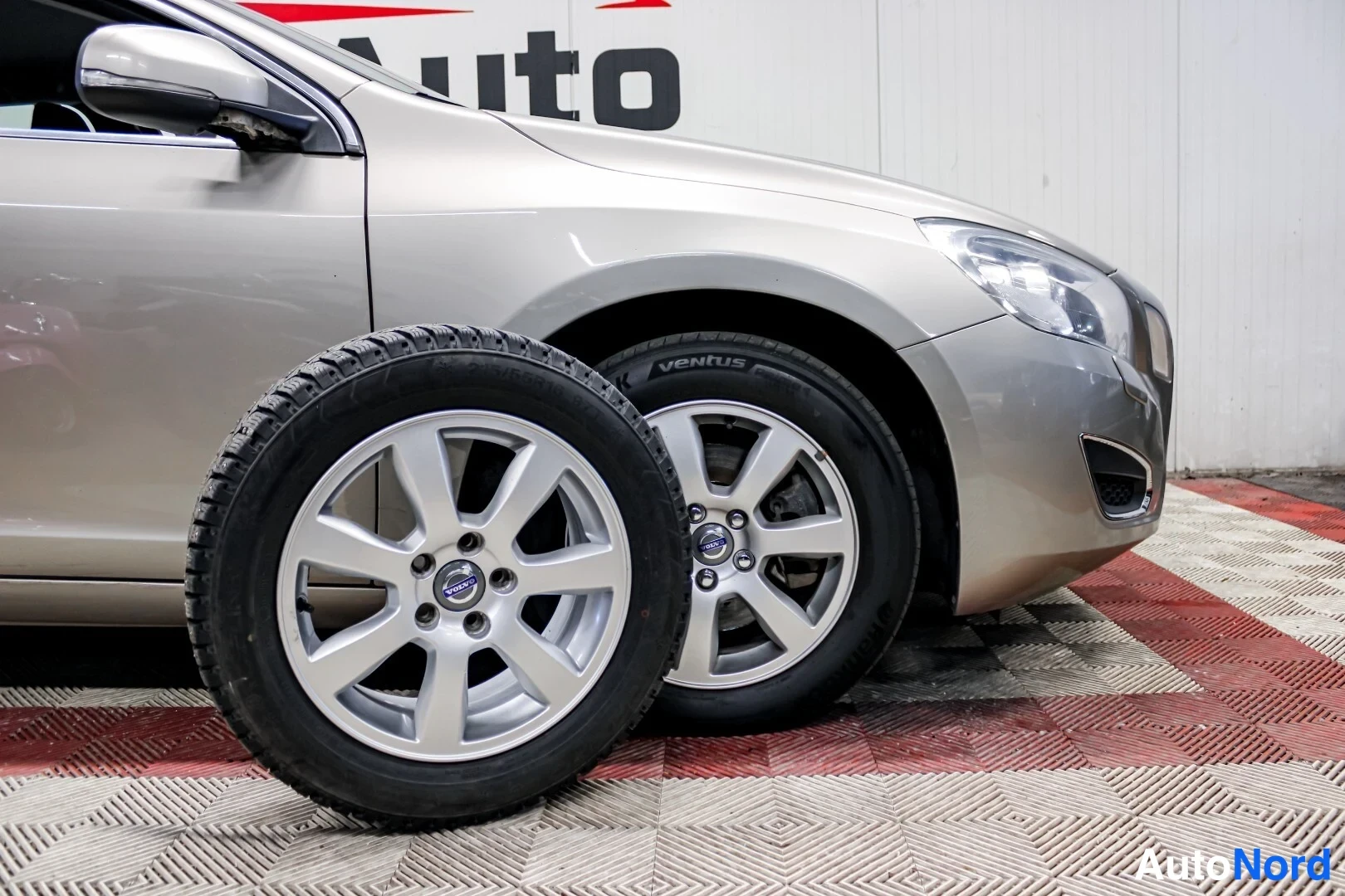 Etuviisto, nokka oikealle: Volvo V60:n etuosa ja kylki kolmasneljännestä oikealta, hopeanvärinen maali, kevytmetallivanne näkyvissä; edessä kyljellä toinen rengas.