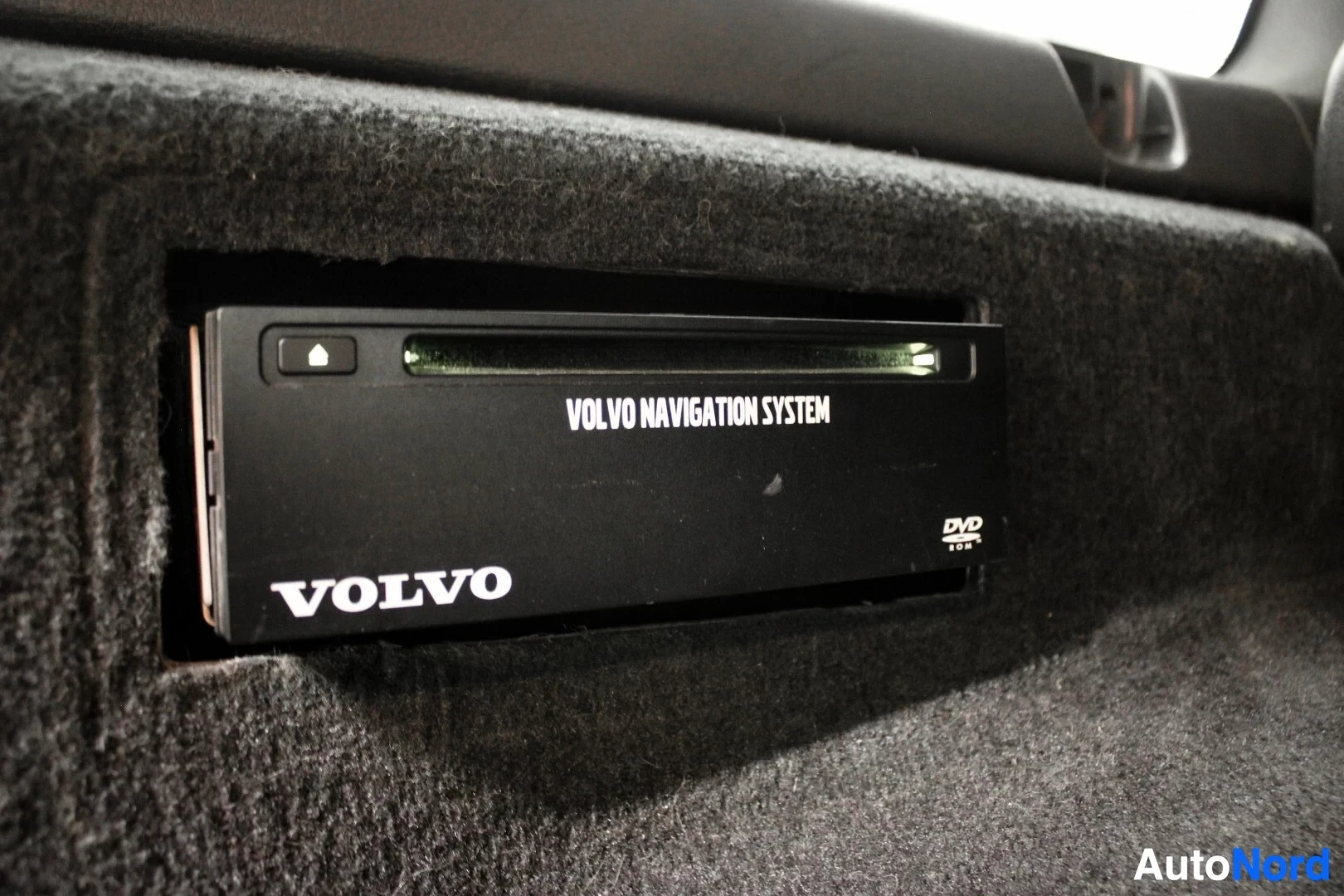 Yksityiskohta: Sisäkuva DVD-soittimesta, jossa lukee 'VOLVO NAVIGATION SYSTEM' ja 'DVD'.