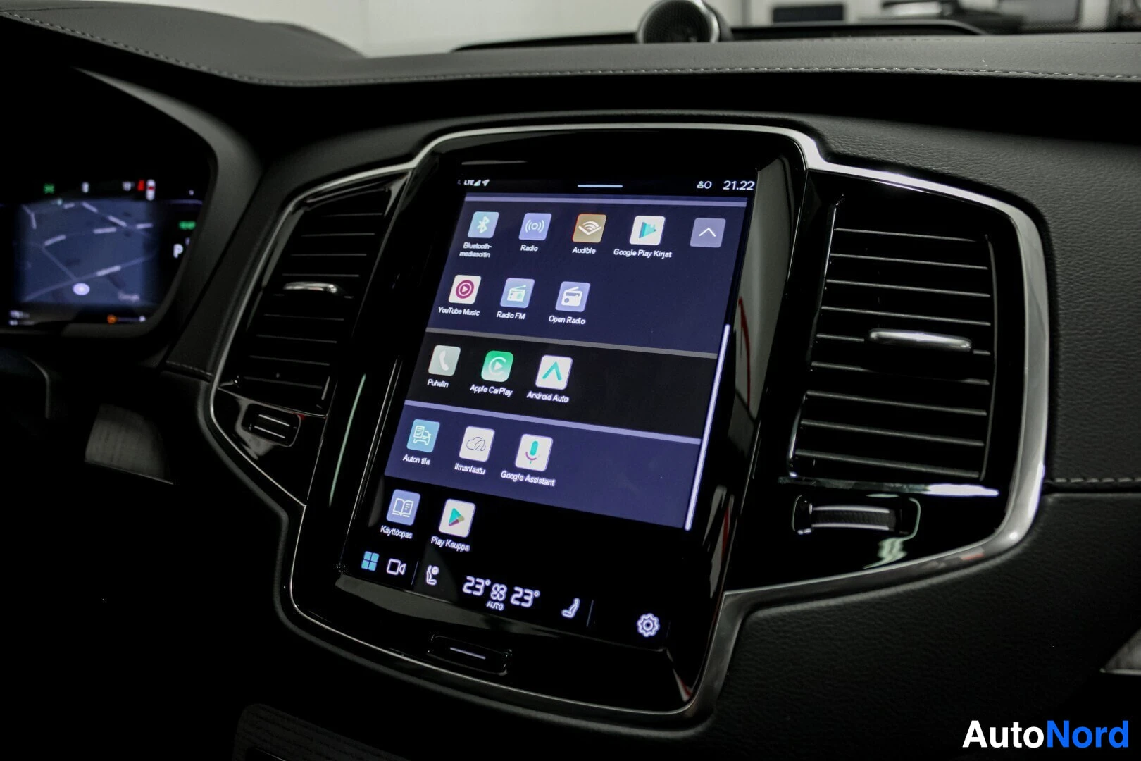 Yksityiskohta: Keskikonsolin näyttö, jossa näkyy useita sovelluskuvakkeita, kuten Apple CarPlay, Android Auto ja Google Assistant.