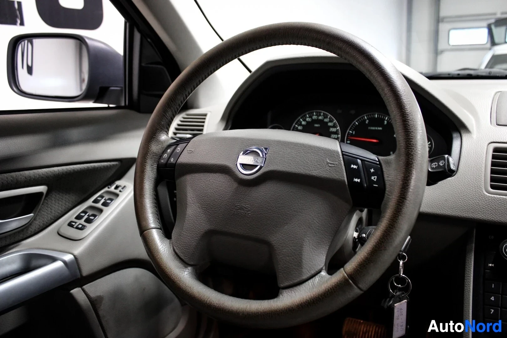 Ohjaamo: Lähikuva ohjauspyörästä ja mittaristosta. Ohjauspyörässä on Volvo-logo ja monitoimipainikkeet.