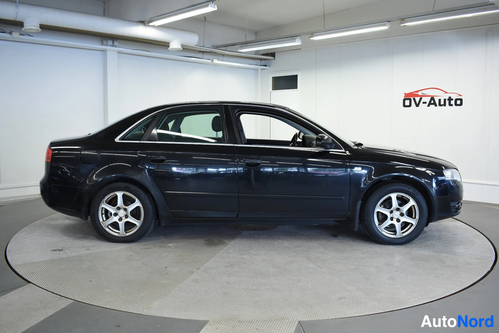 Sivulta: Musta Audi A4:n oikea kylki kuvattuna suoraan sivulta. Autossa on kevytmetallivanteet.