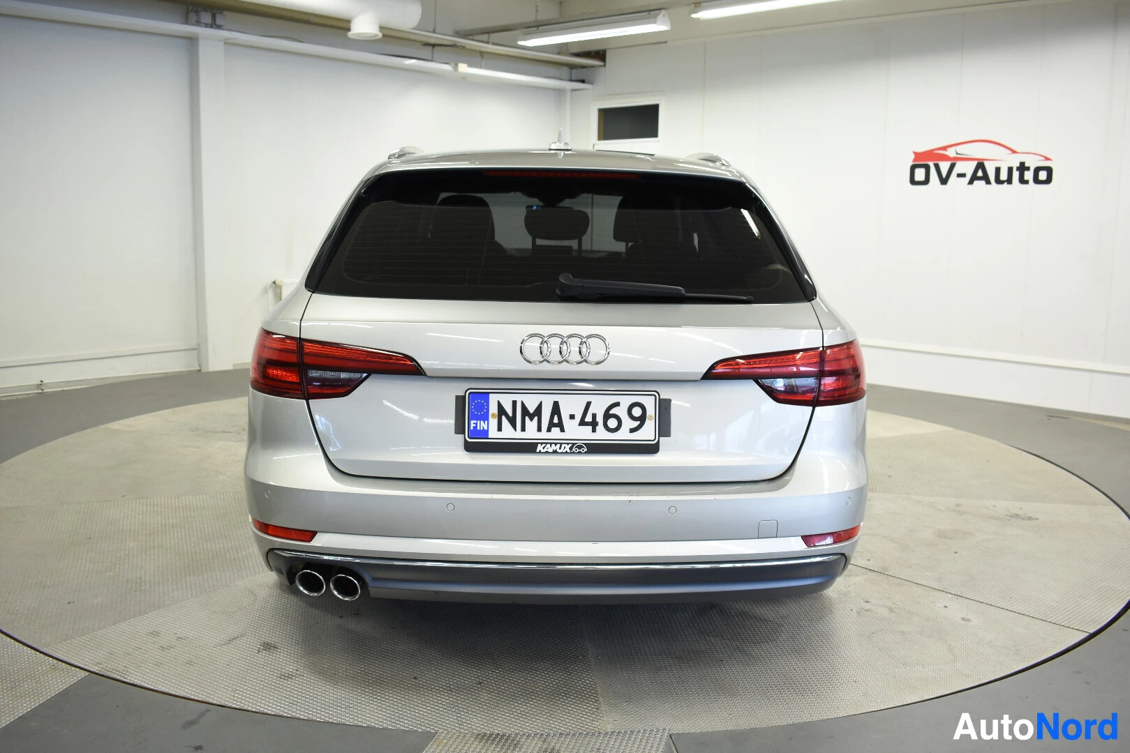 Takaa: Hopeanvärinen farmariauto takaa päin kuvattuna. Takana näkyy Audi-logo, rekisterikilpi ja kaksi pakoputken ulostuloa.