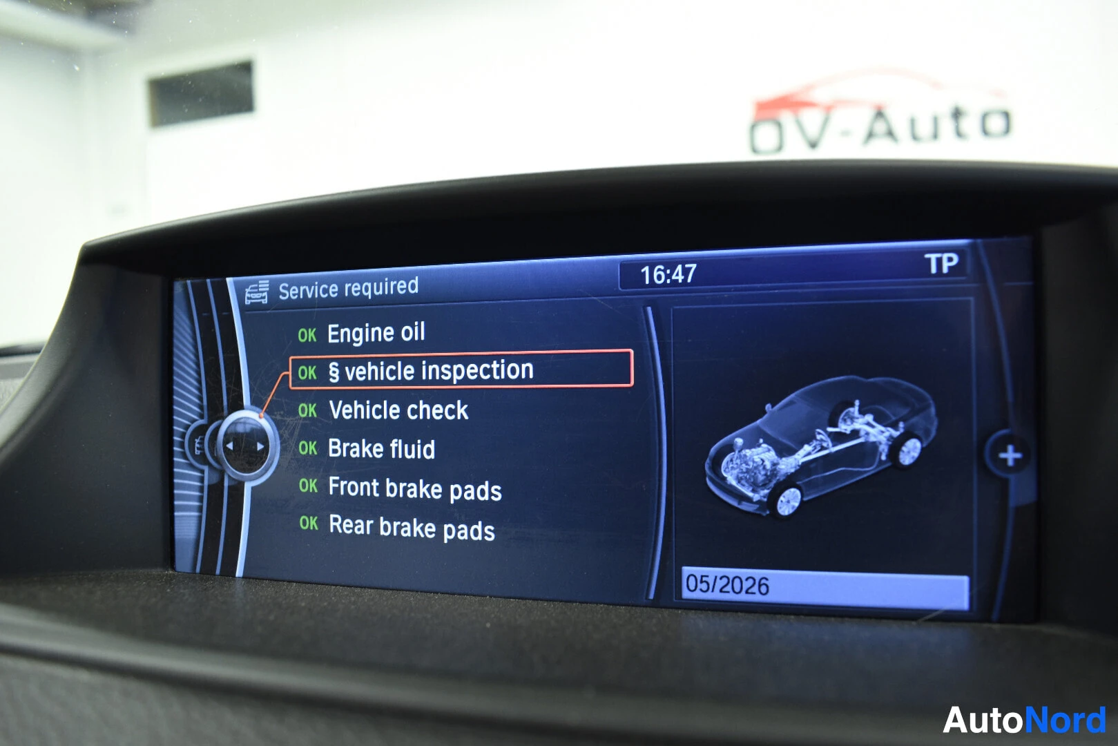 Yksityiskohta: Ajoneuvon multimediajärjestelmän näyttö, jossa on valikko "Service required" ja lista huoltokohteista. "Vehicle inspection" on korostettu ja sen vieressä lukee