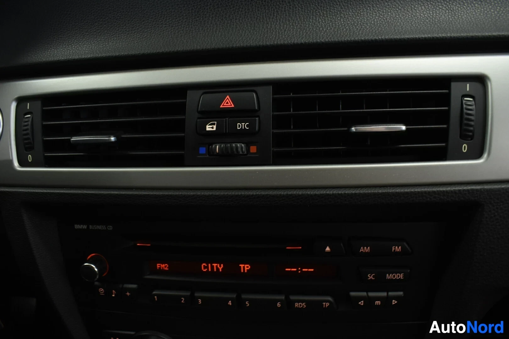 Yksityiskohta: Kojelaudan yläosassa on ilmanvaihtoaukot, hätävilkkupainike ja DTC-painike. Sen alapuolella on BMW Business CD -radio.