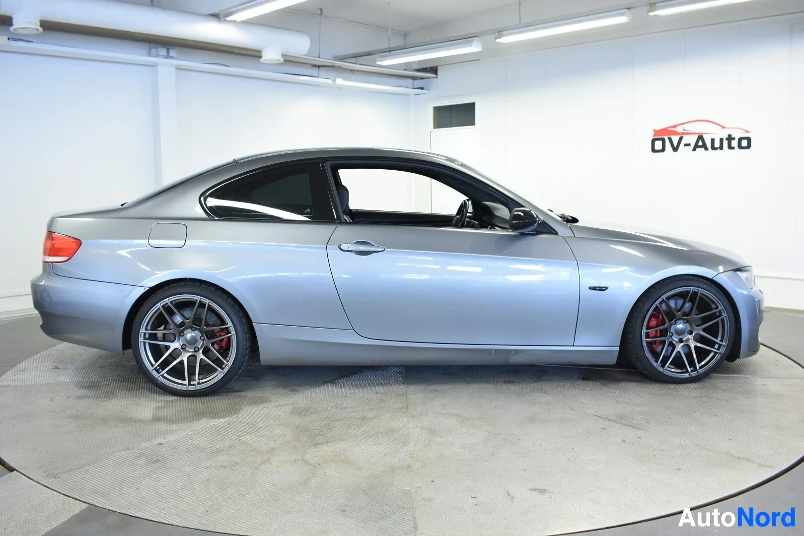 Sivulta: Harmaa BMW:n coupé kuvattuna suoraan oikealta kyljeltä. Autossa on tummat monipuolaiset alumiinivanteet, joiden takana näkyy punaiset jarrusatulat.