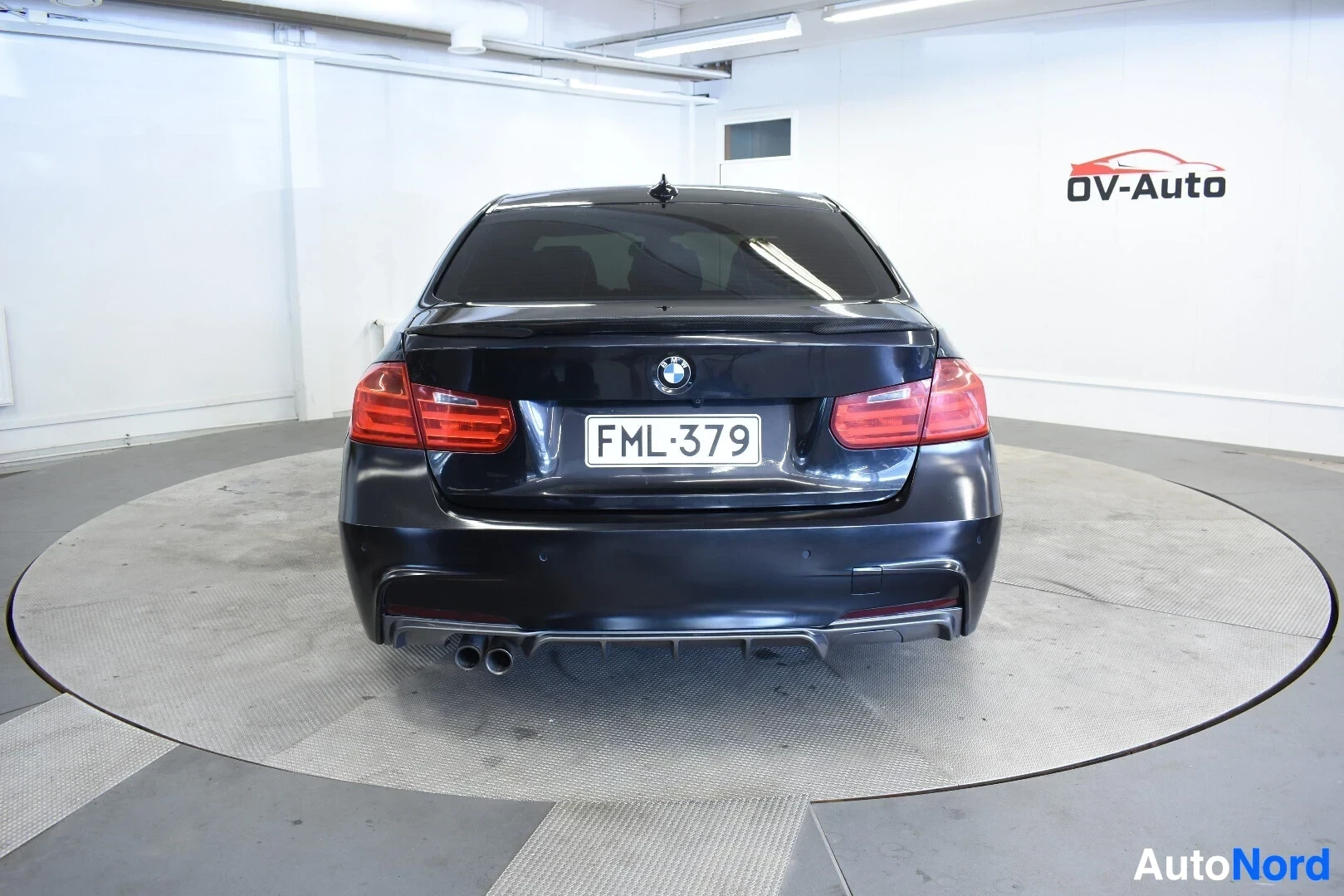 Takaa: Musta BMW sedan takaa kuvattuna, rekisterikilvessä on teksti. Takavalot ja pakoputkien päät näkyvät selvästi