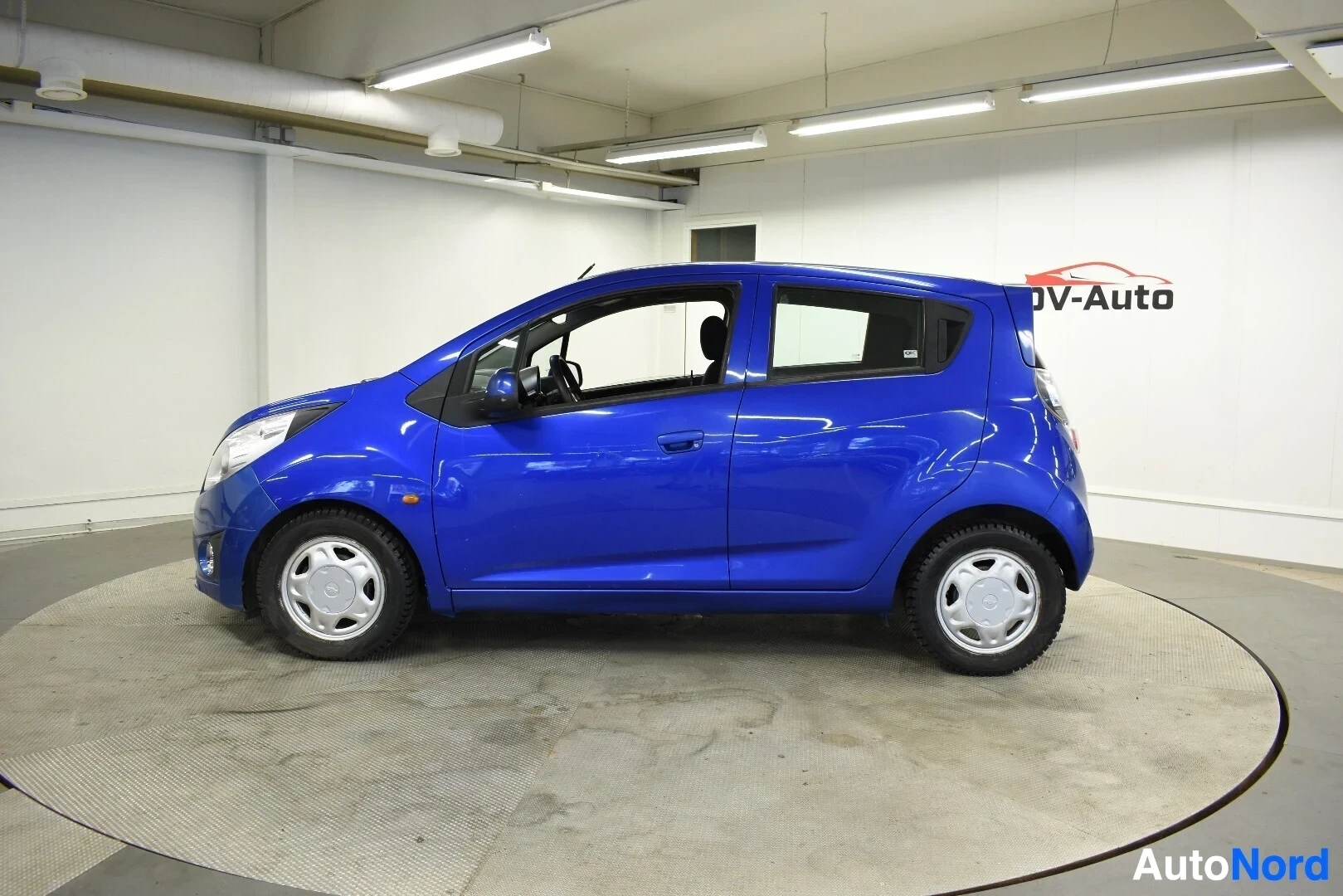 Sivulta: Sininen henkilöauto kuvattuna vasemmalta sivulta. Autossa on peltivanteet.