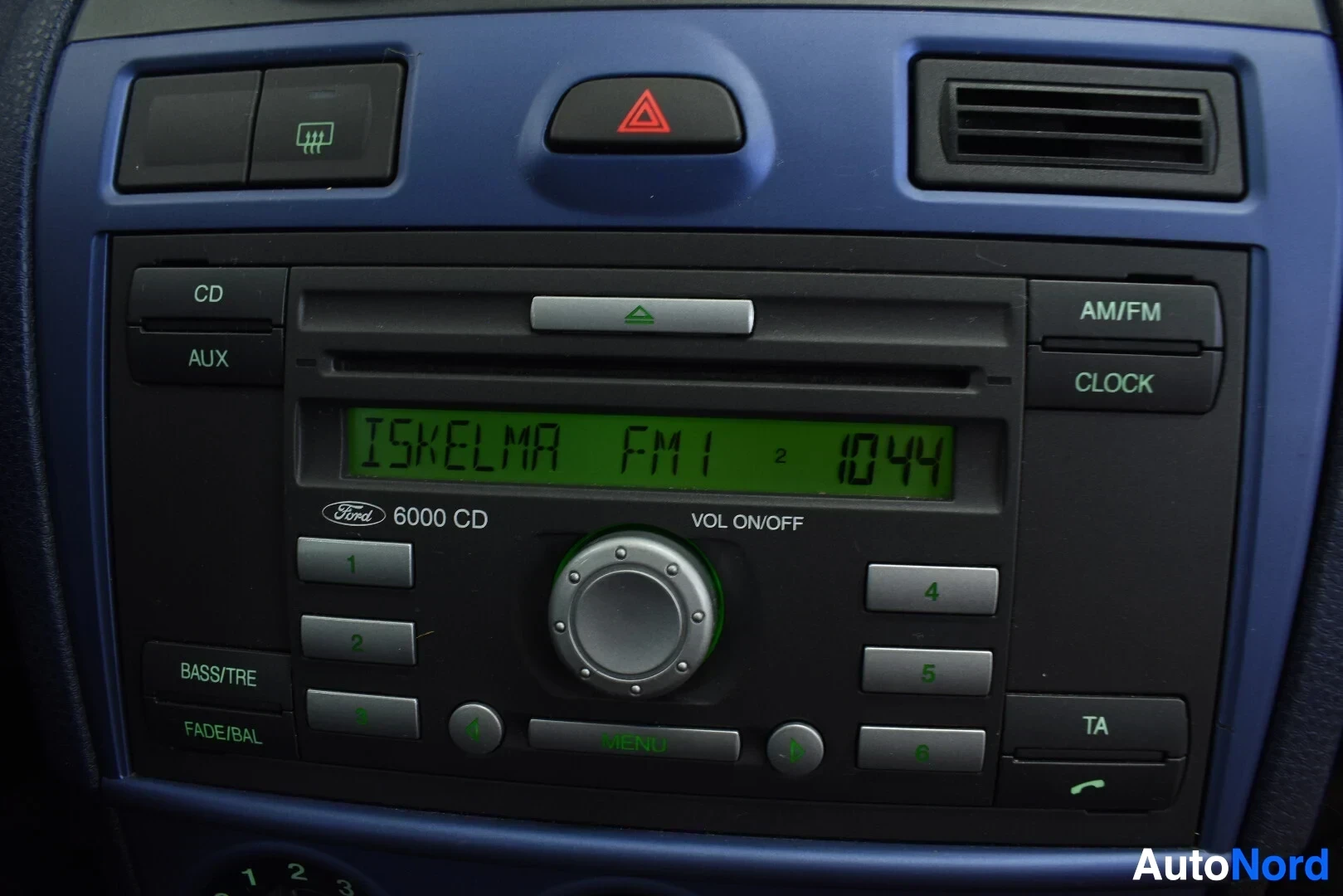 Yksityiskohta: Lähikuva auton keskikonsolin radio-CD-soittimesta, jossa lukee "ISKELMA FM1 1044".