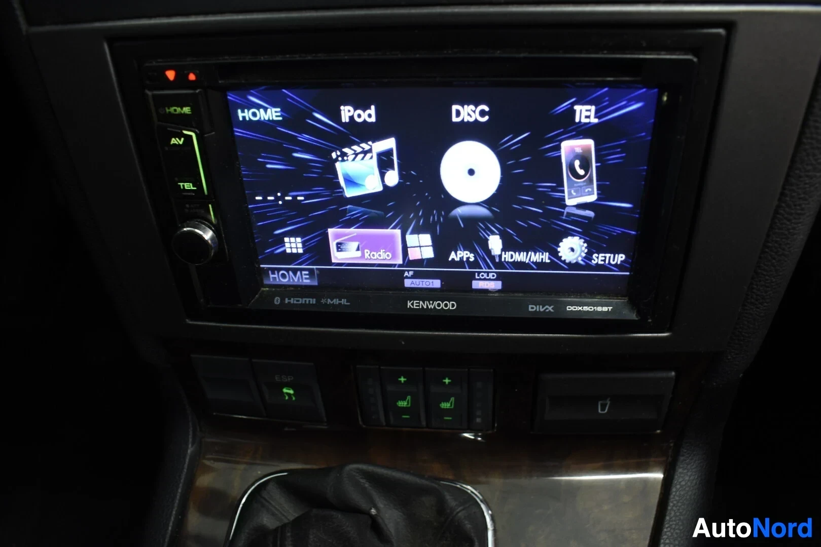 Yksityiskohta: Lähikuva auton tietoviihdejärjestelmän näytöstä, jossa on näkyvissä "HOME", "iPod", "DISC", "TEL", "Radio", "APPS", "HDMI/MHL" ja "SETUP" -valinnat. Näytön alao