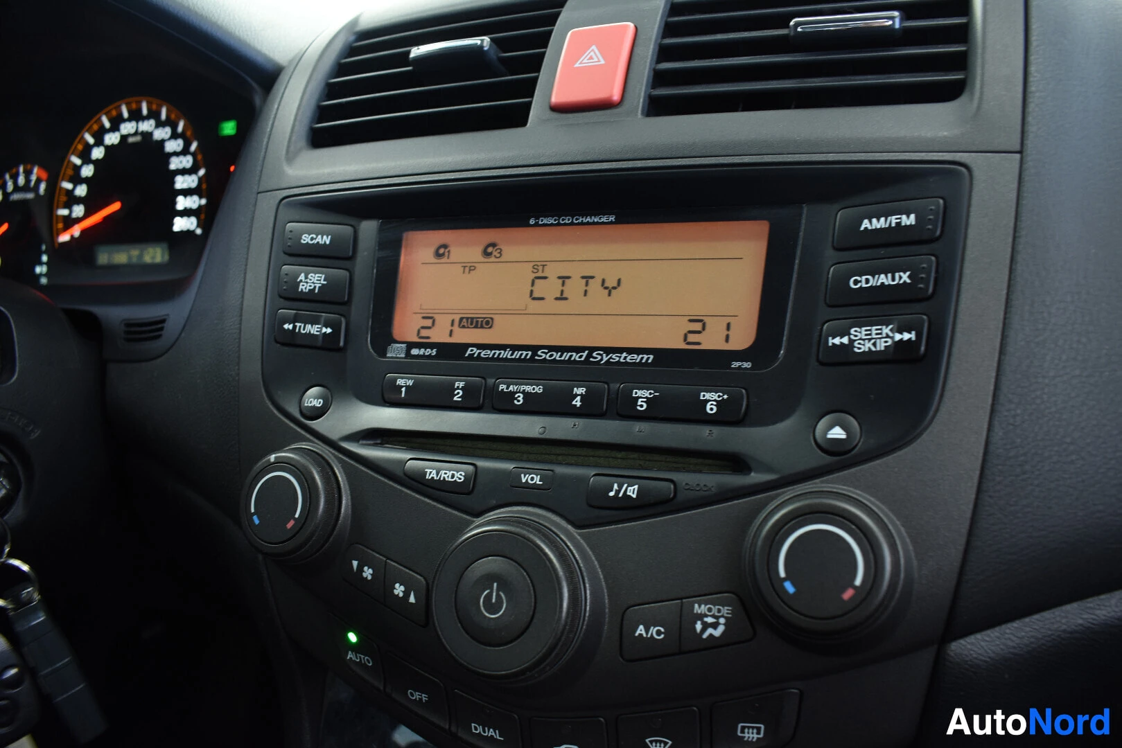 Yksityiskohta: Lähikuva auton keskikonsolista. Radion näytöllä lukee "CITY" ja "Premium Sound System". Alla näkyy CD-vaihtajan painikkeet "DISC 1-6".