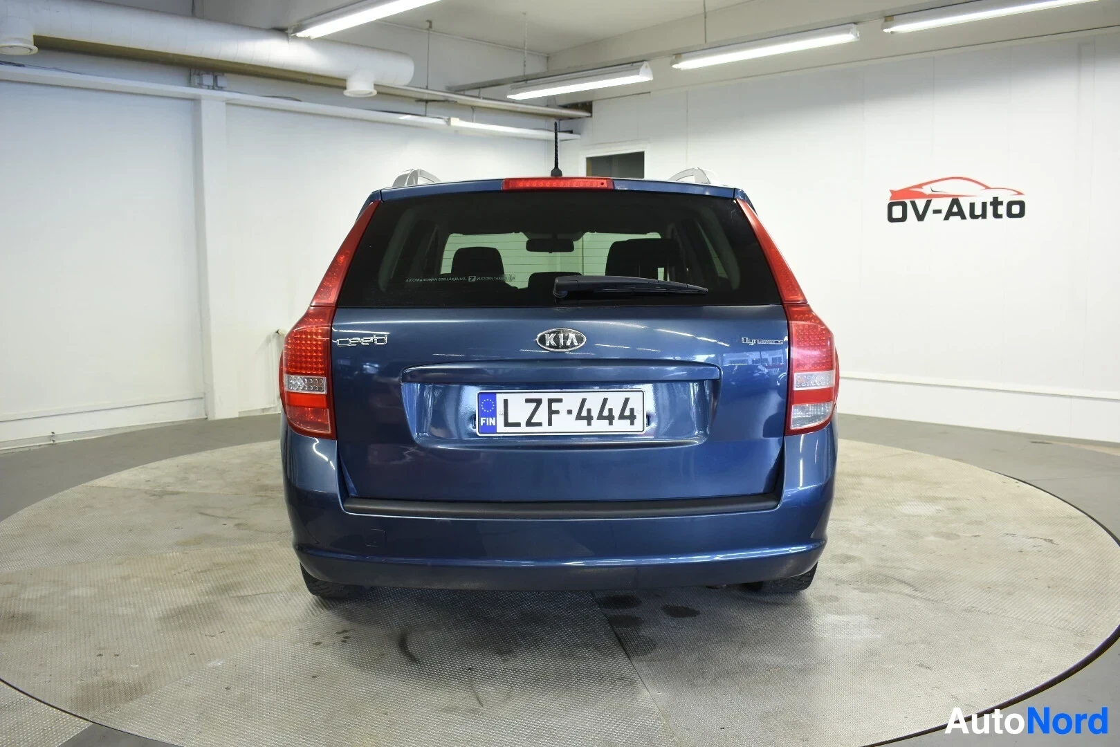 Takaa: Sininen farmariauto takaa kuvattuna kääntöalustalla sisätiloissa.