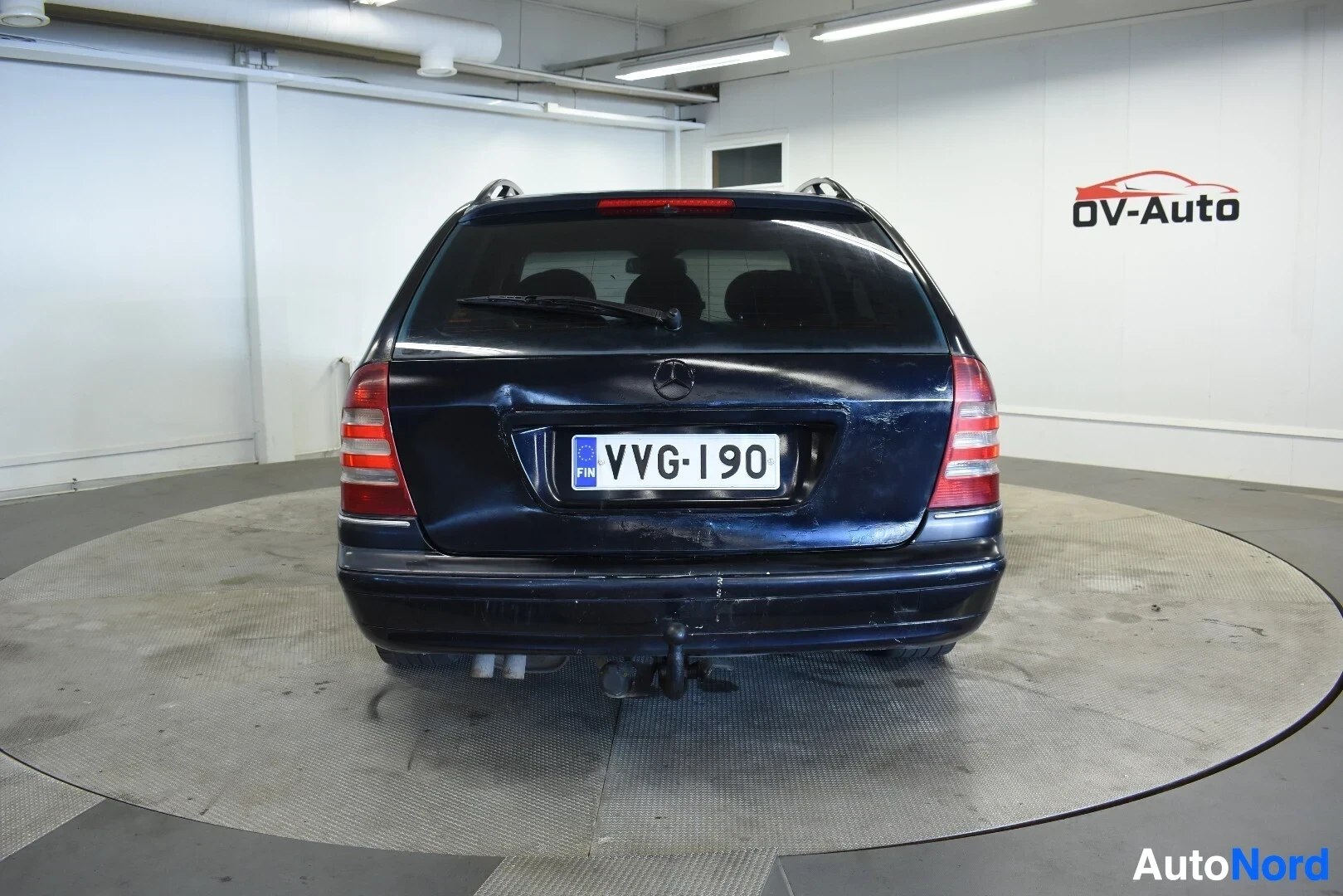 Takaa: Tummanvihreä farmariauto takaa. Autossa on vetokoukku.